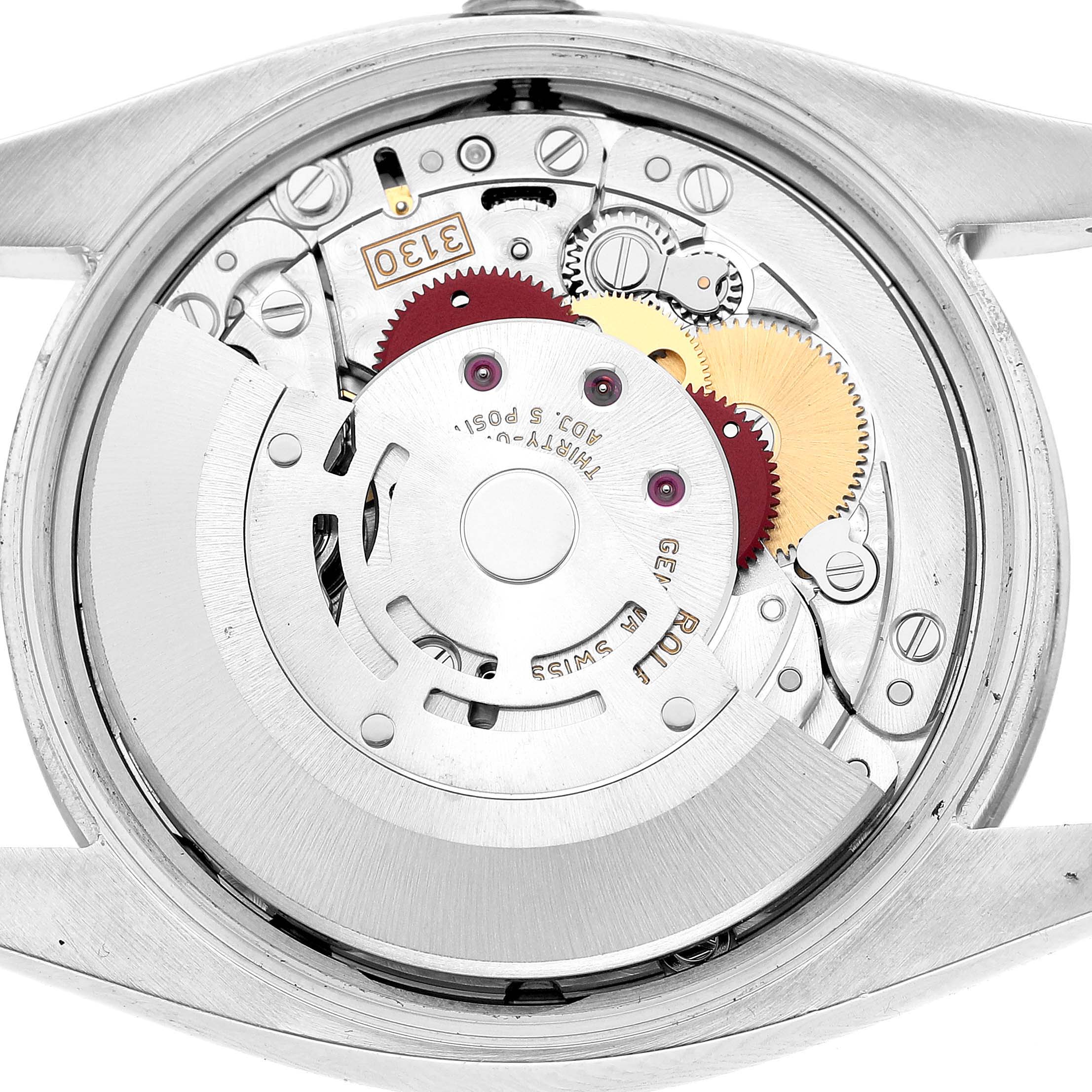 The image shows the back view of the Rolex Oyster Perpetual 114200 Men's Stainless Steel Silver Dial, highlighting its intricate movement components.