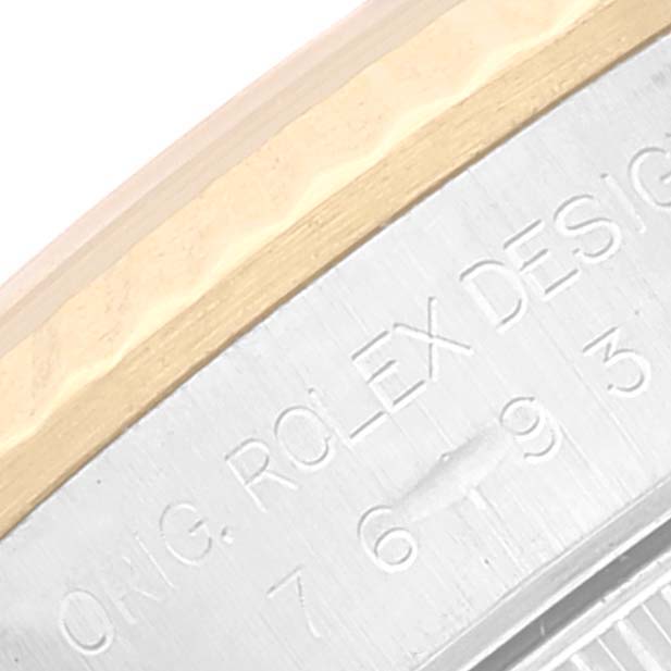 The image shows the engraved side of the bezel and case back of a Rolex Oyster Perpetual 76193 Women's Steel and Gold (two tone) Champagne Dial 76193 Women's Steel and Gold (two tone) Champagne Dial watch at a close-up angle.