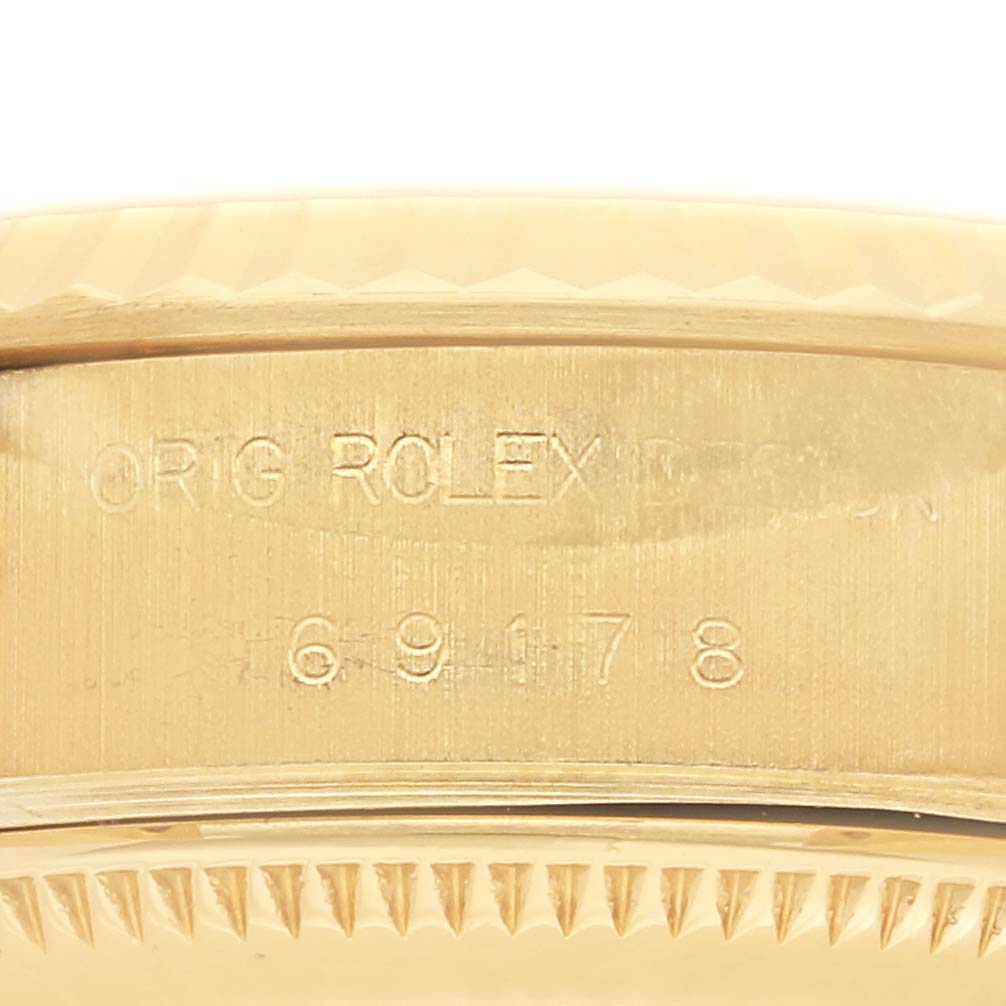 The image shows a close-up of the side of a Rolex President 69178 Women's Yellow Gold Black Dial 69178 Women's Yellow Gold Black Dial watch, highlighting the engraved serial numbers.