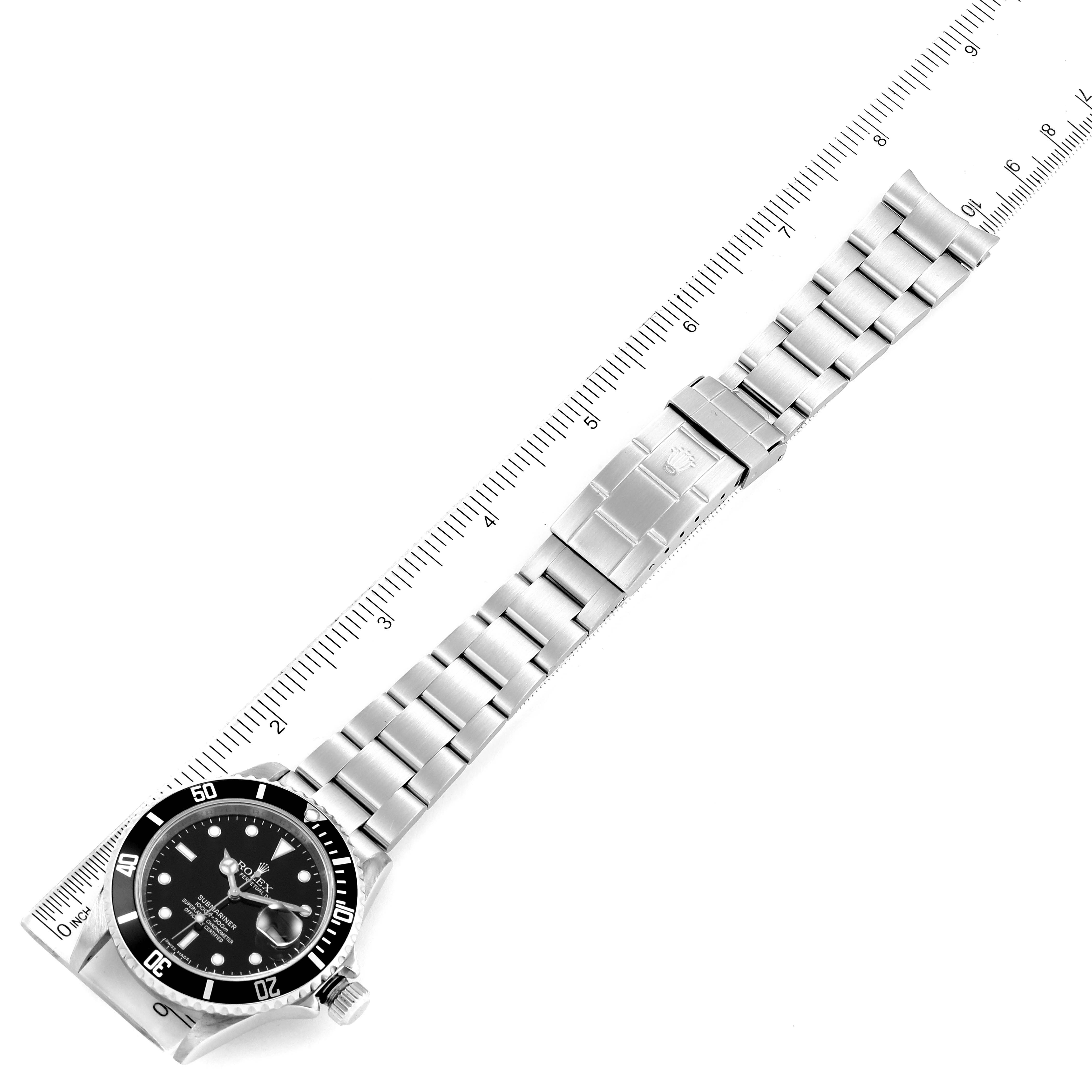 The image shows the full length of a Rolex Submariner 16610 Men's Stainless Steel Black Dial 16610 Men's Stainless Steel Black Dial watch with its stainless steel bracelet, placed diagonally along a ruler.