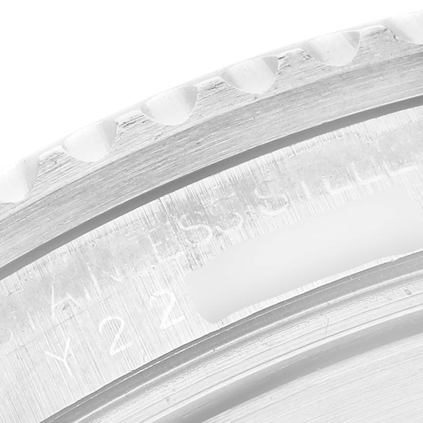 The image shows a close-up of the Rolex Submariner 16610 Men's Stainless Steel Black Dial's bezel edge and part of its case, highlighting the engraved text.