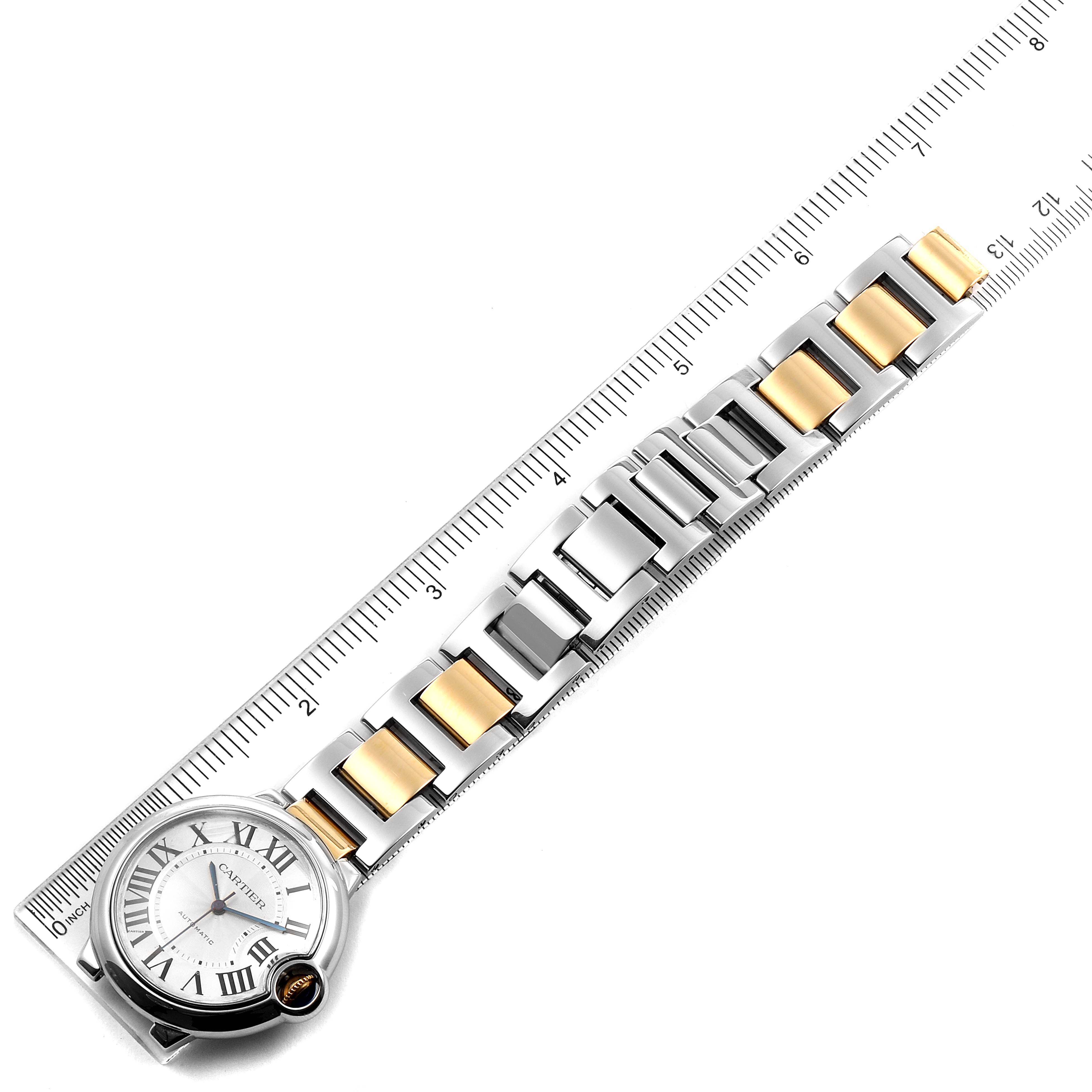 The image shows a top-down view of a Cartier Ballon Bleu W2BB0012 Women's Steel and Gold (two tone) Silver Dial W2BB0012 Women's Steel and Gold (two tone) Silver Dial watch, focusing on the face and bracelet with a ruler beside it.