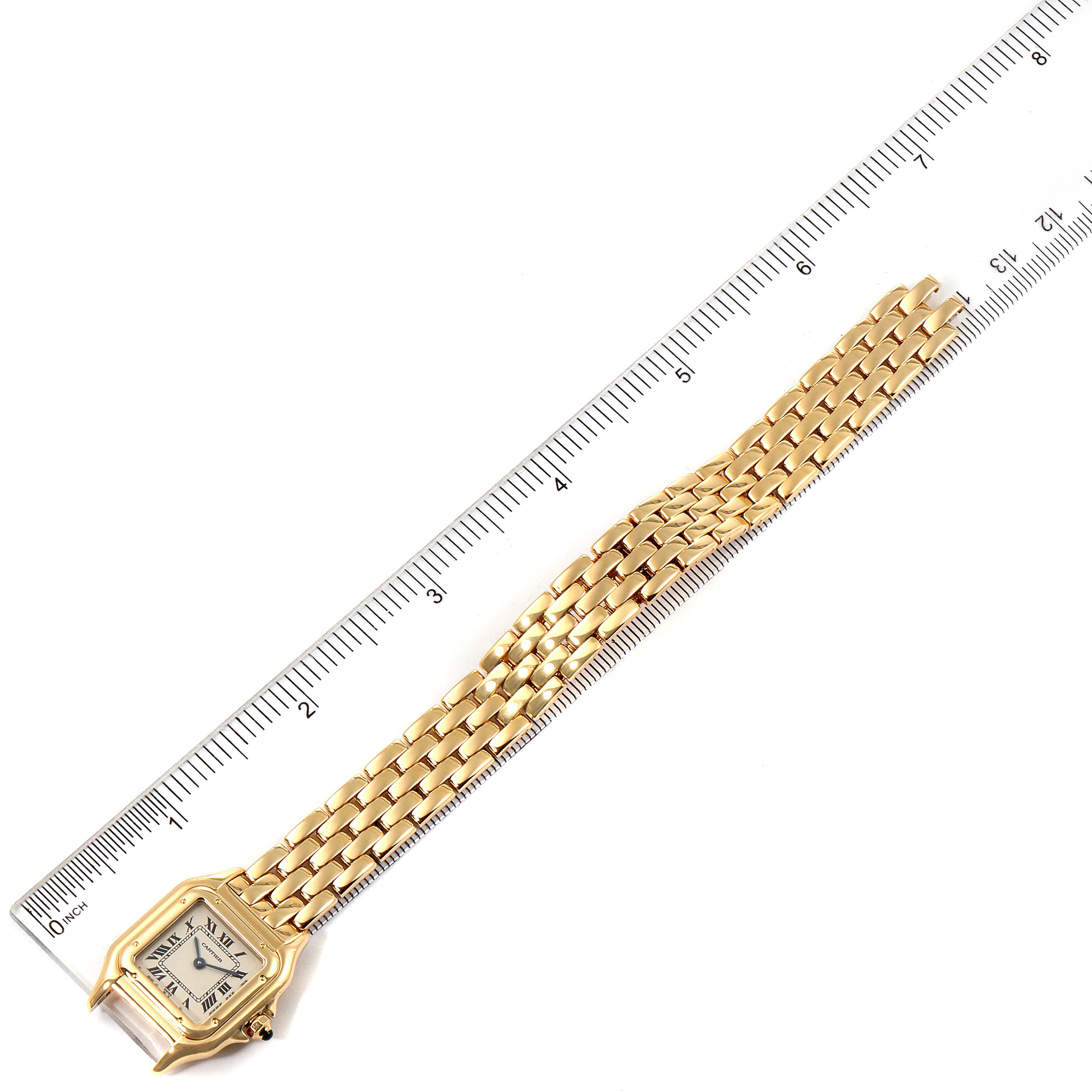 The image shows a top-down view of a Cartier Panthere W25022B9 Women's Yellow Gold Silver Dial W25022B9 Women's Yellow Gold Silver Dial watch including its rectangular face and gold bracelet alongside a ruler.
