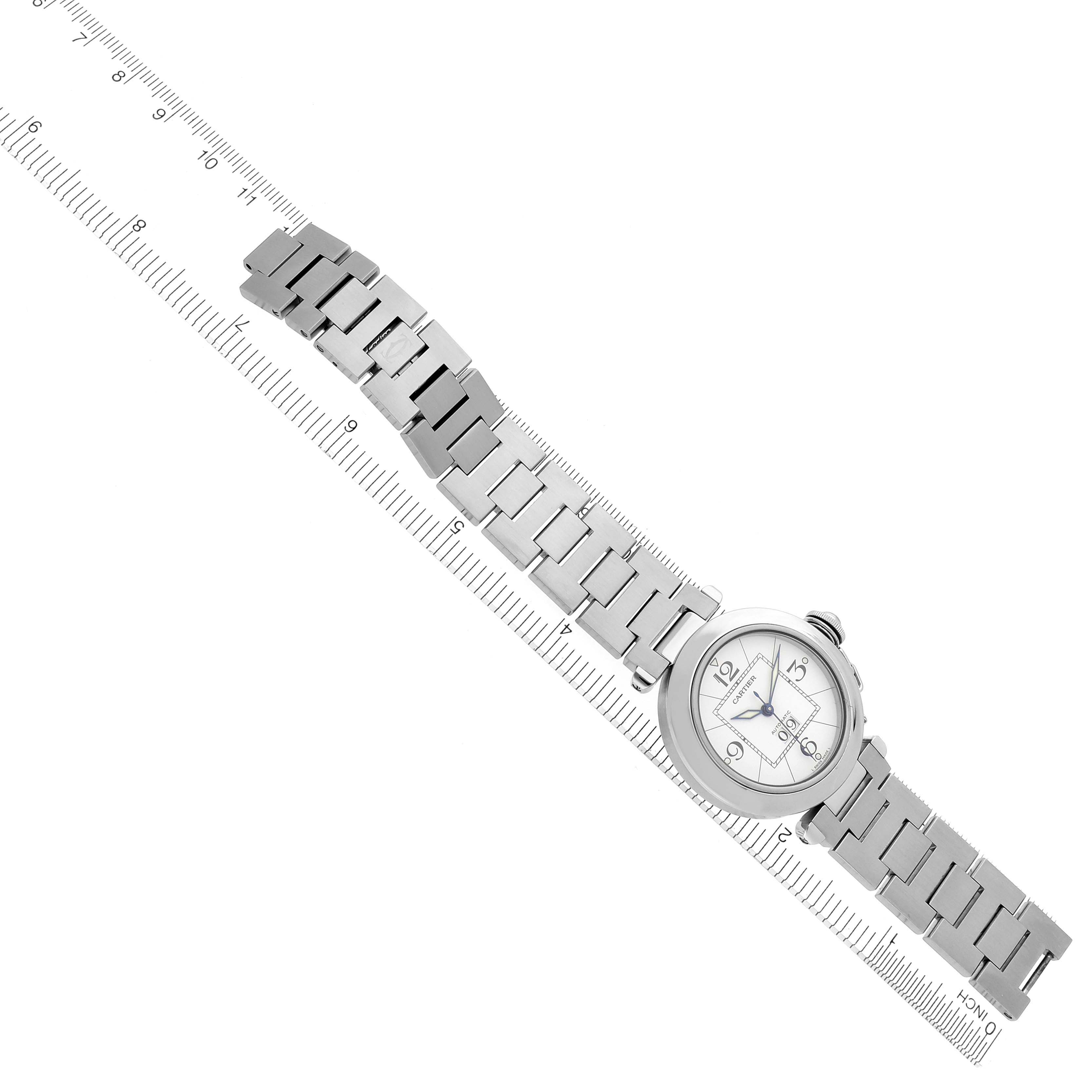 The Cartier Pasha W31055M7 Men's Stainless Steel White Dial W31055M7 Men's Stainless Steel White Dial watch is shown at a slight angle featuring the face and full link bracelet alongside a ruler.