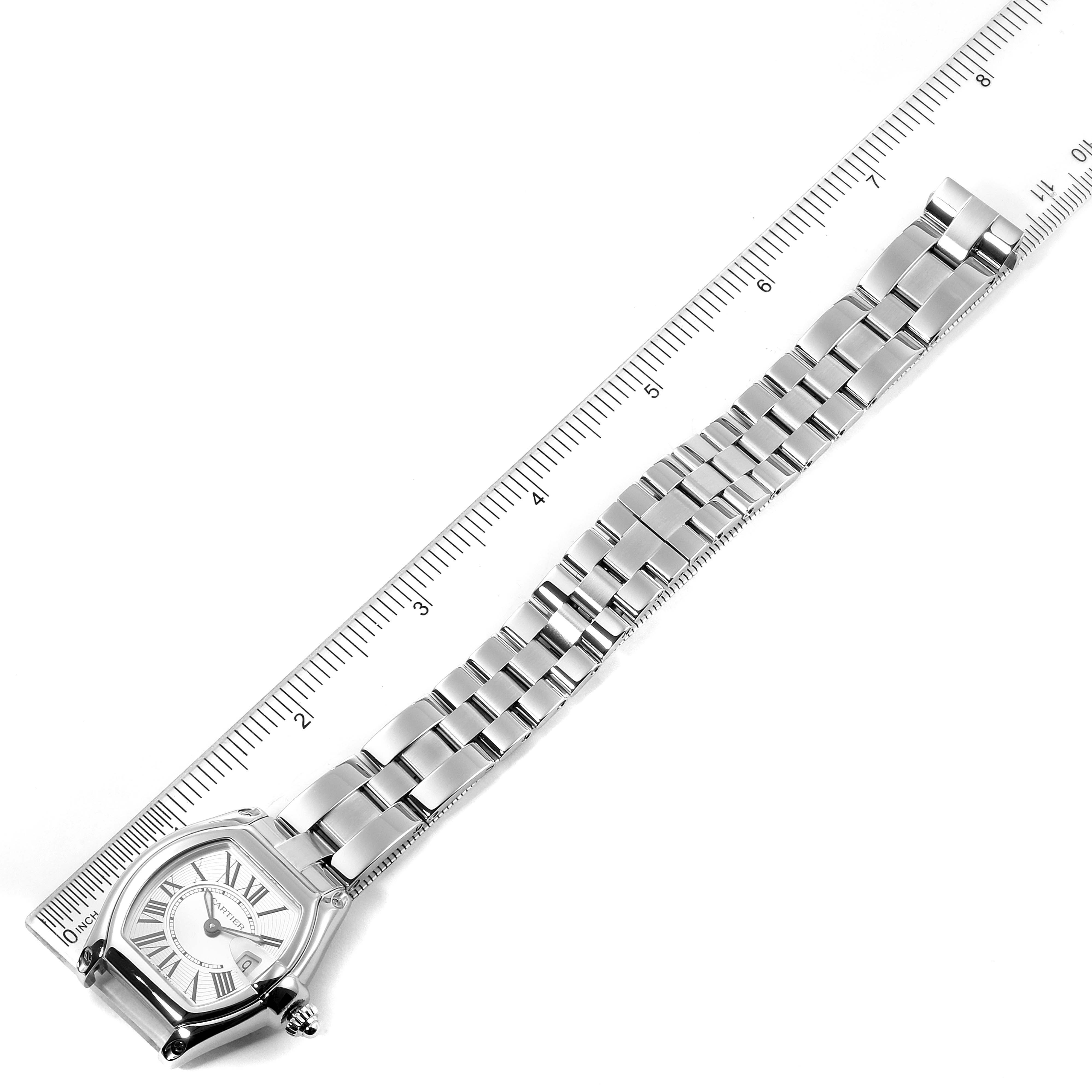 The Cartier Roadster W62016V3 Women's Stainless Steel Silver Dial W62016V3 Women's Stainless Steel Silver Dial watch is shown from an overhead angle, displaying the case, bezel, dial, and metal bracelet laid along a ruler.