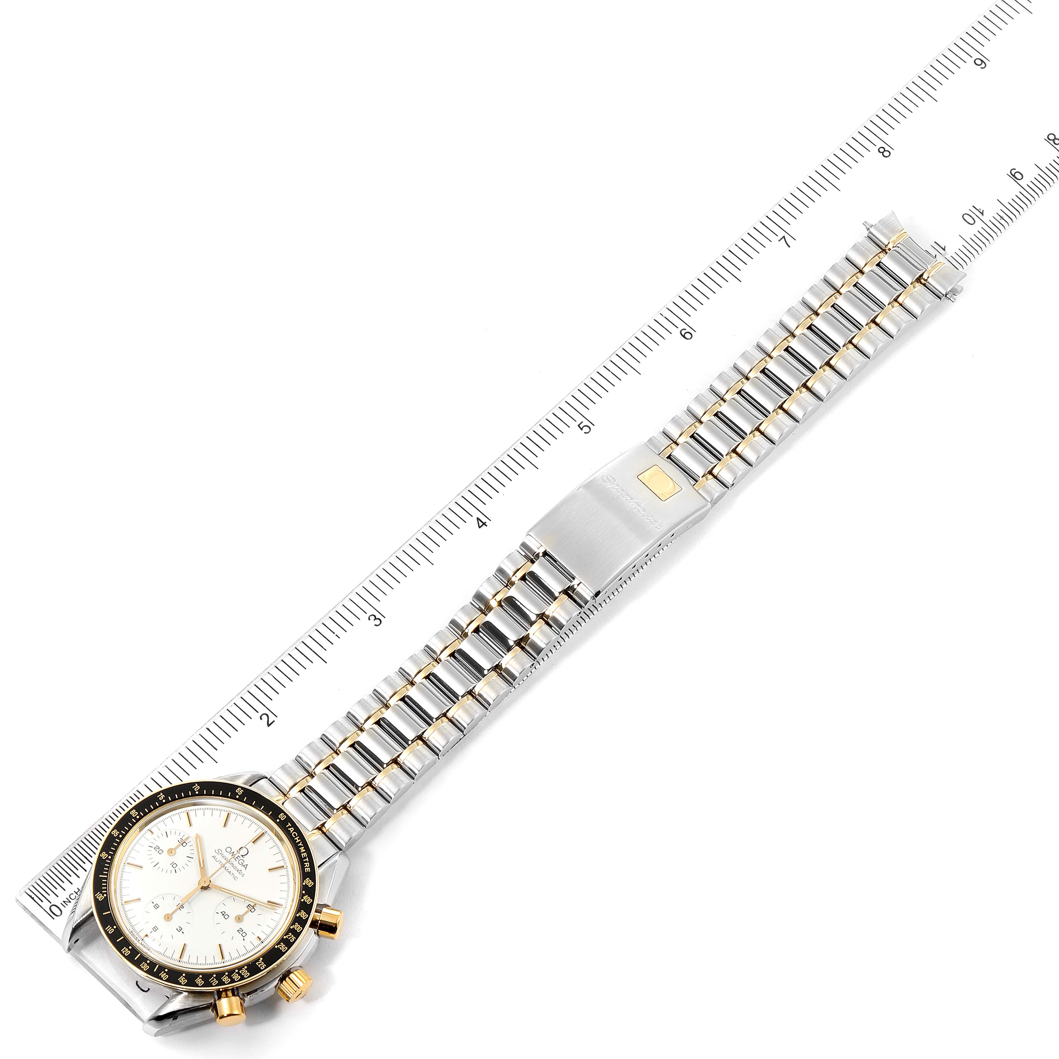This image shows an Omega Speedmaster 3310.20.00 Men
s Steel and Gold (two tone) White Dial 3310.20.00 Men
s Steel and Gold (two tone) White Dial watch laid flat with a ruler, highlighting its bezel, dial, buttons, and full metal strap.
