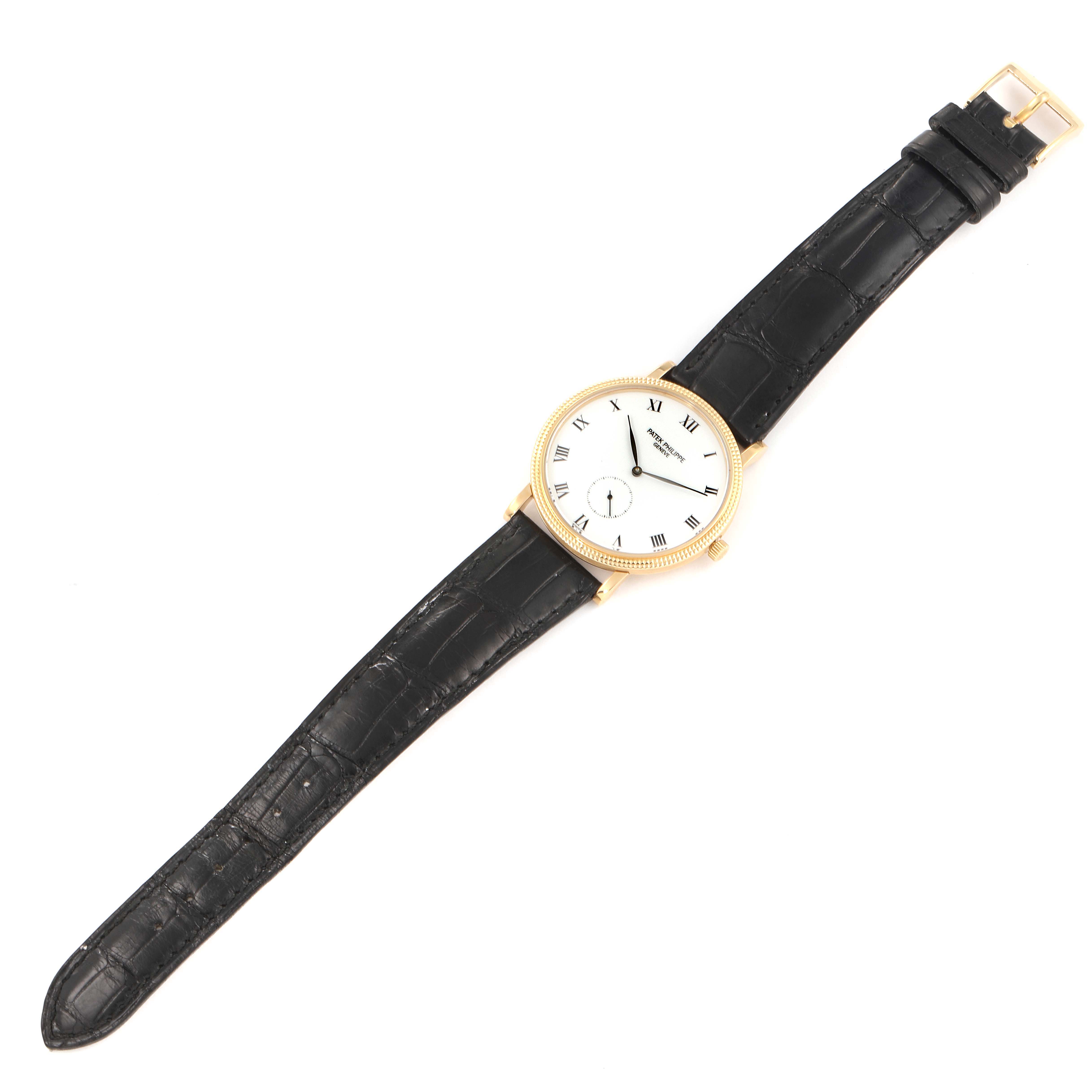 The image shows a top-down view of a Patek Philippe Calatrava 3919 Men's Yellow Gold White Dial 3919 Men's Yellow Gold White Dial watch with a black leather strap and a gold case.