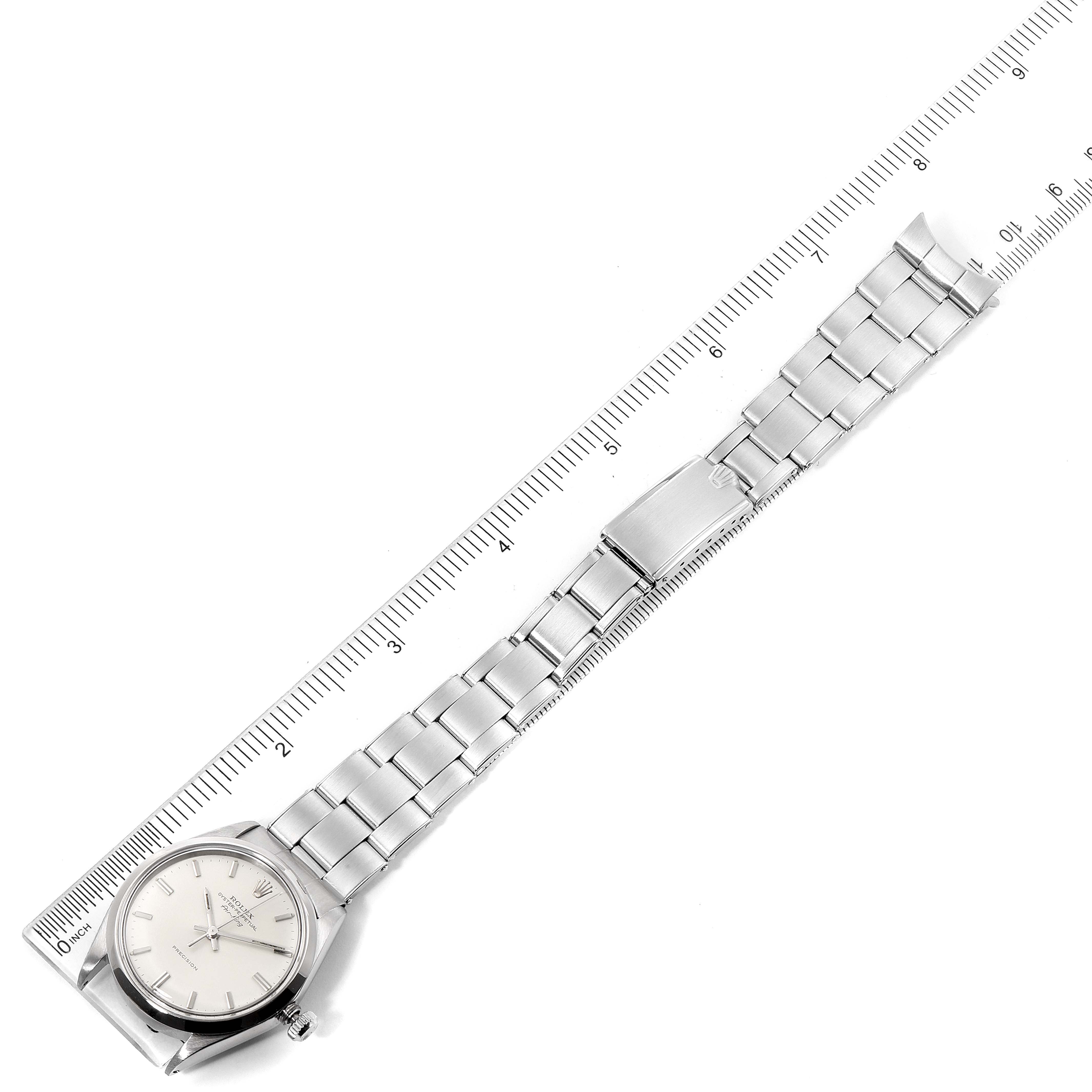 The image shows a top-down view of a Rolex Vintage Collection 5500 Men's Stainless Steel Silver Dial 5500 Men's Stainless Steel Silver Dial watch with a metal bracelet and a ruler for scale.