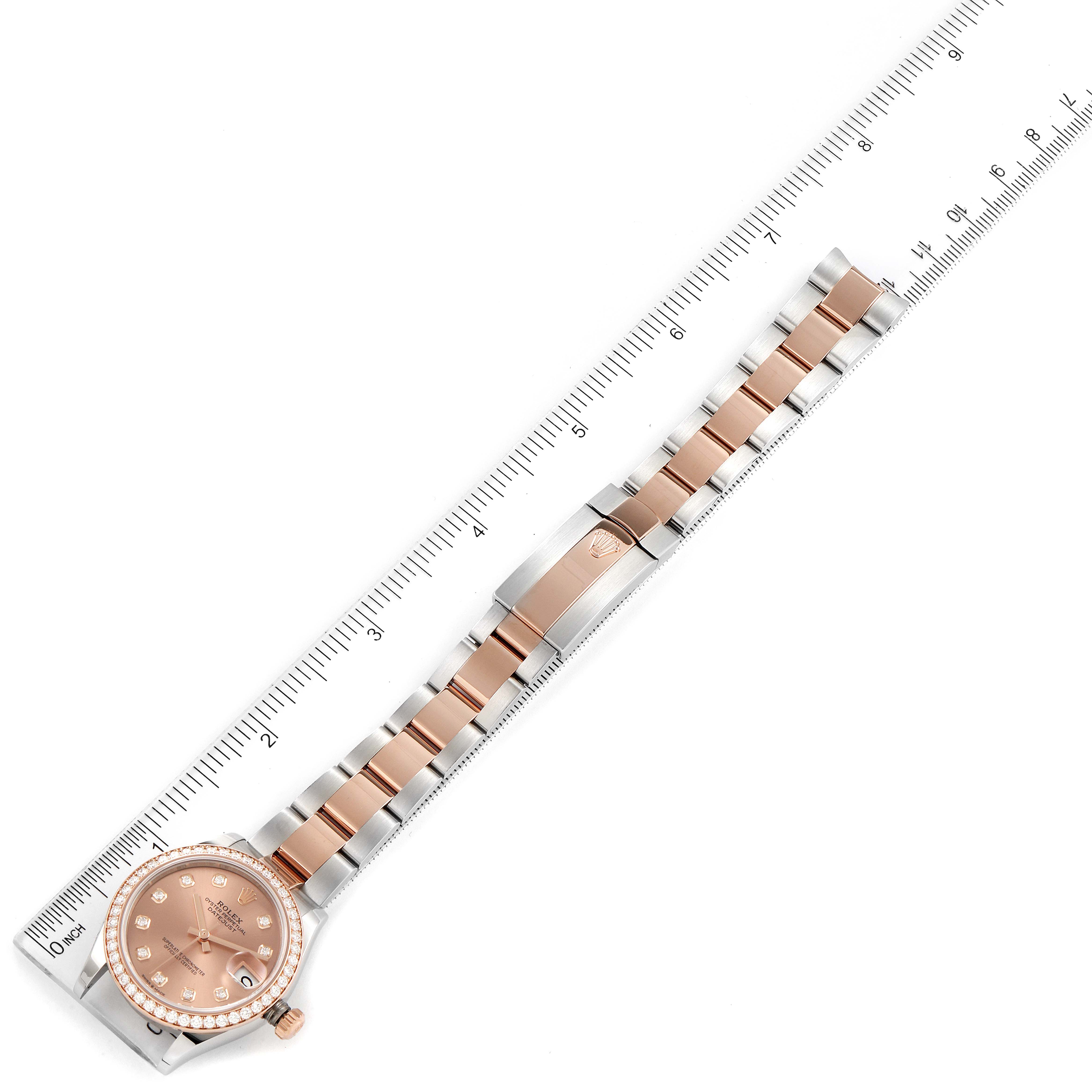 This image shows a Mid-Size Rolex watch laid flat with a stainless steel and rose gold bracelet, alongside a ruler for scale.