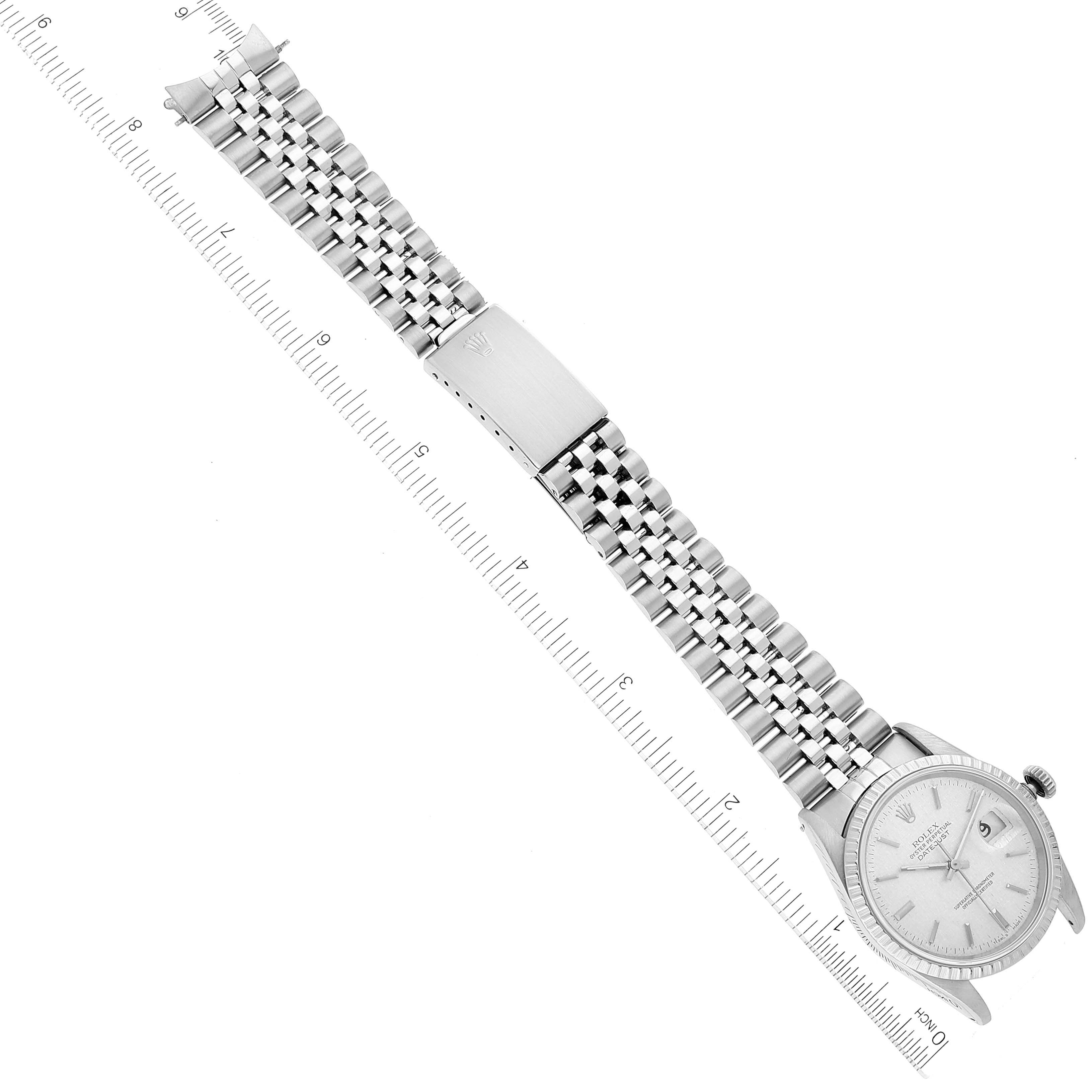 The image shows a top-down view of a Rolex Datejust 16220 Men's Stainless Steel Silver Dial 16220 Men's Stainless Steel Silver Dial watch, displaying the face, bracelet, and clasp alongside a ruler for scale.