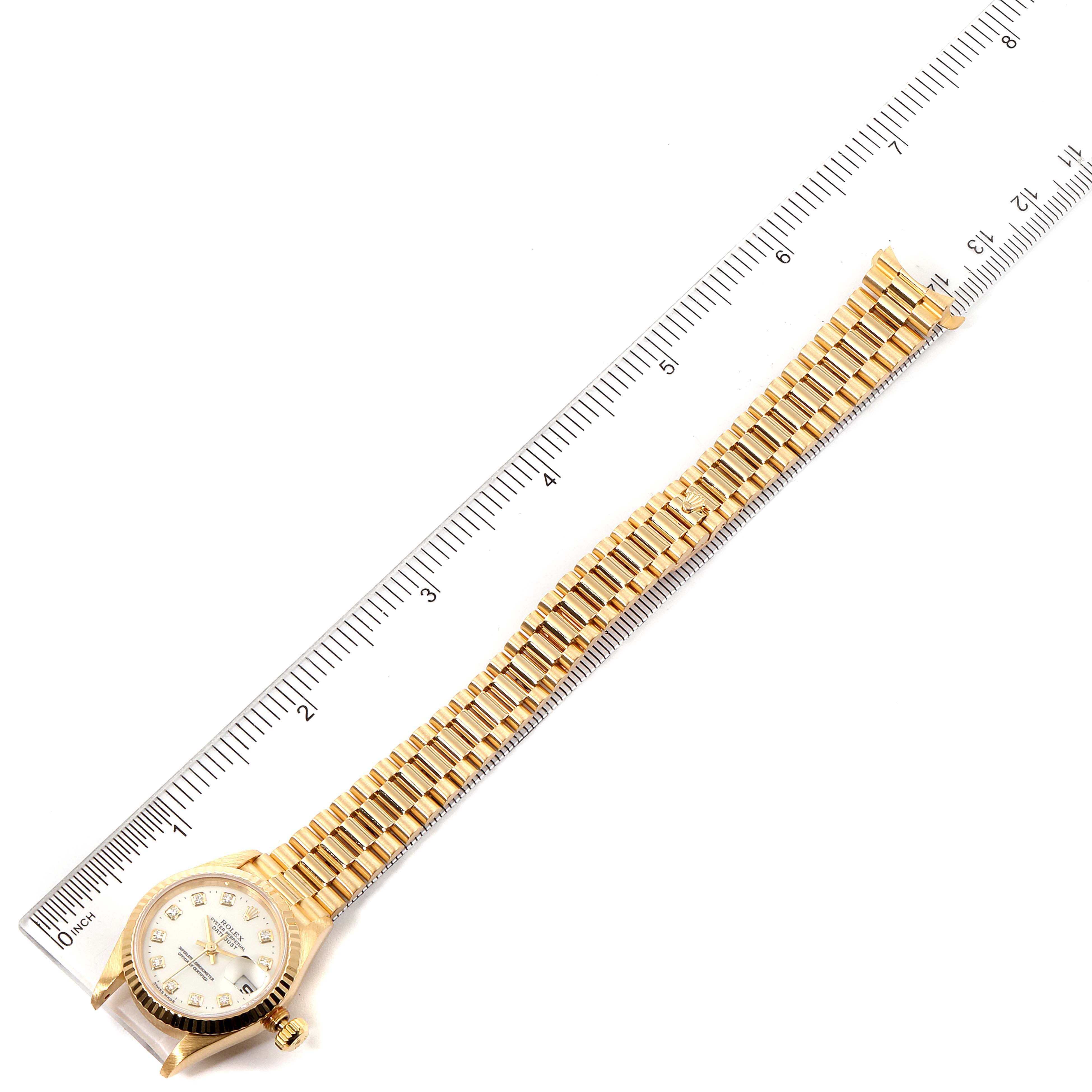 The image shows a Rolex President 69178 Women's Yellow Gold White Dial 69178 Women's Yellow Gold White Dial model watch laid flat, alongside a ruler, displaying its face and bracelet.