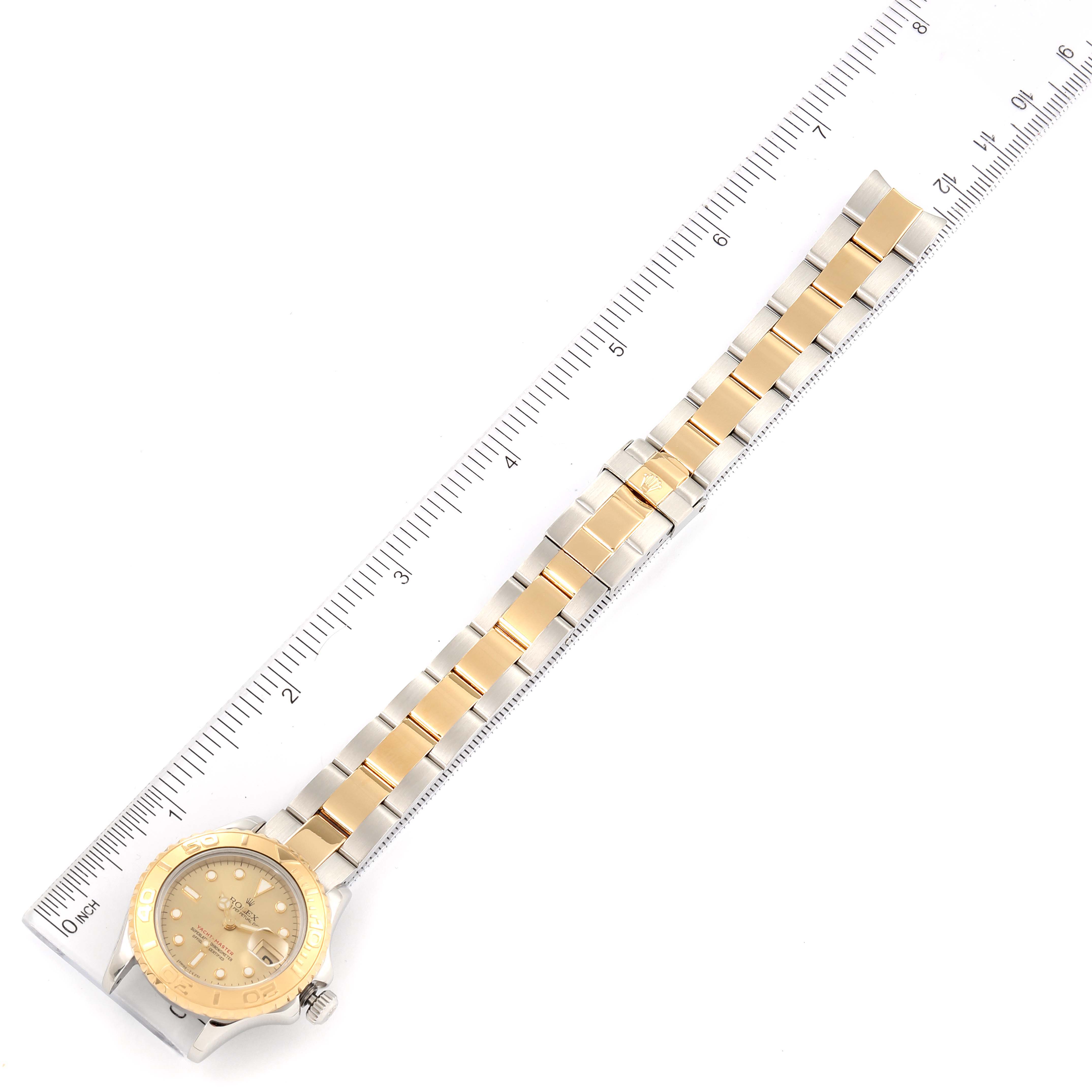 The image shows a Rolex Yacht-Master 69623 Women's Steel and Gold (two tone) Champagne Dial 69623 Women's Steel and Gold (two tone) Champagne Dial watch laid flat, highlighting the gold and silver bracelet, bezel, dial, and crown alongside a ruler.