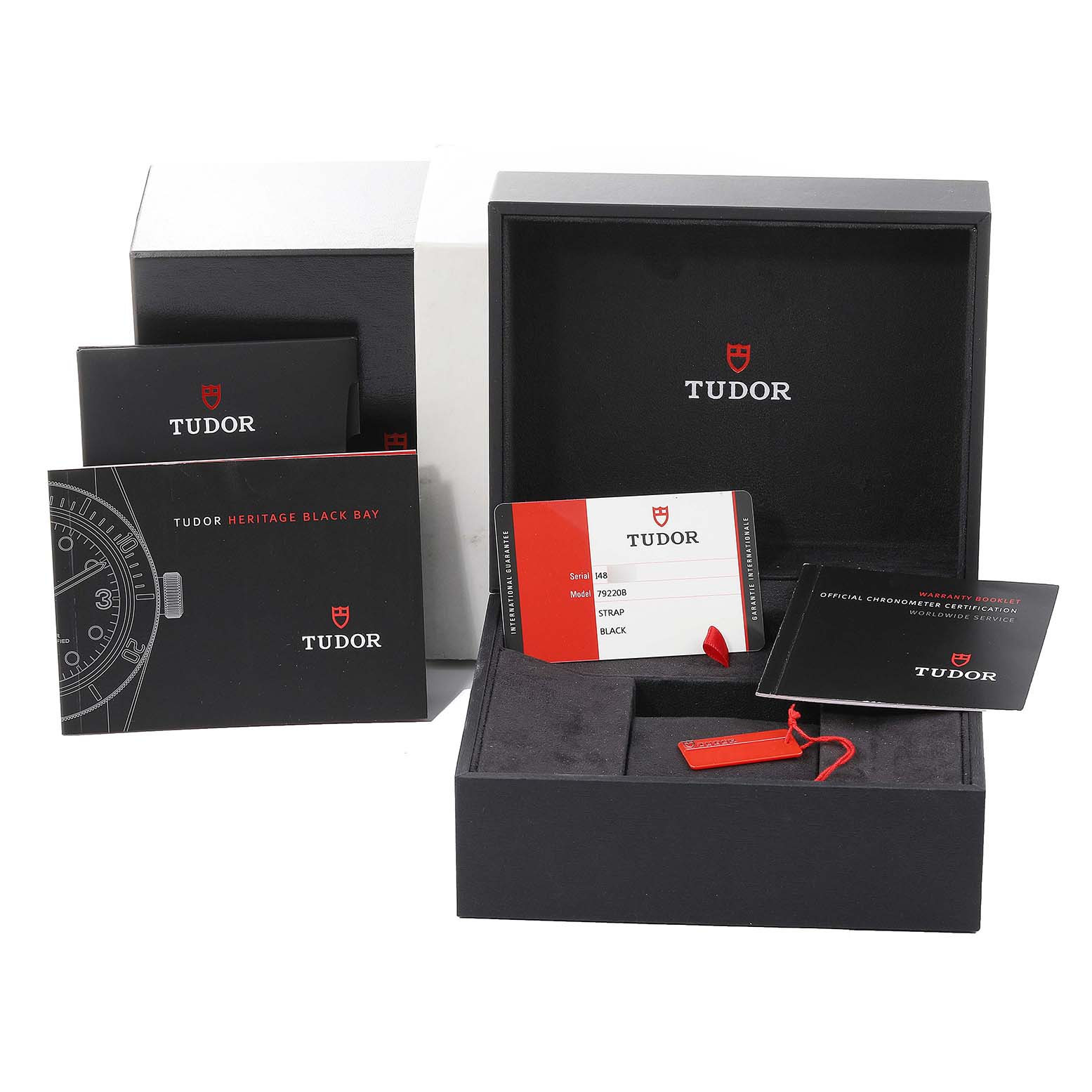 The image displays the packaging and documentation of the Tudor Heritage Black Bay 79220 Men's Stainless Steel Black Dial 79220 Men's Stainless Steel Black Dial, including the box, tags, and certification cards.