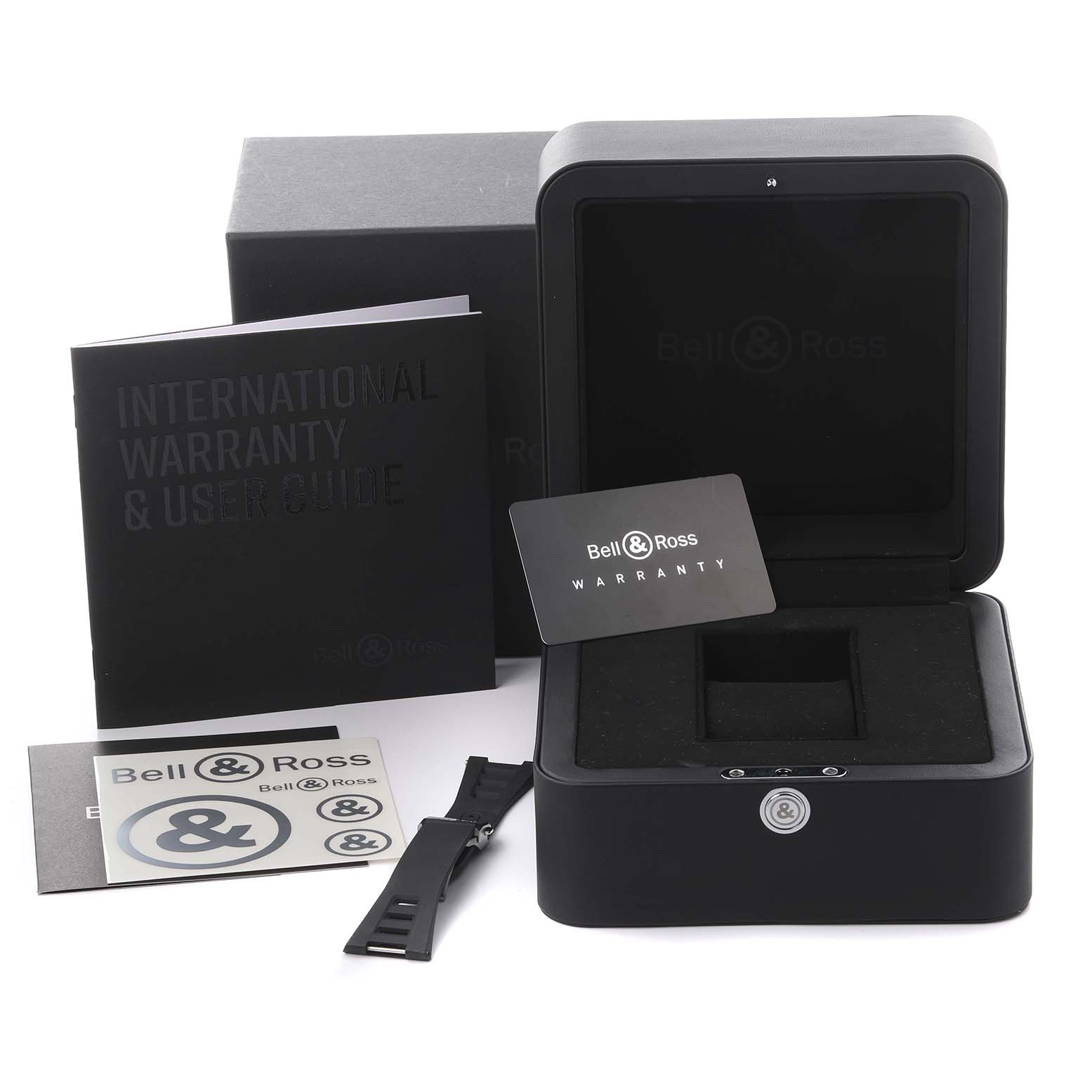 The image shows the Bell & Ross Urban BRX5R-BL-ST Men's Stainless Steel Black Dial BRX5R-BL-ST Men's Stainless Steel Black Dial watch box, warranty card, booklet, extra strap, and stickers from a front angle.