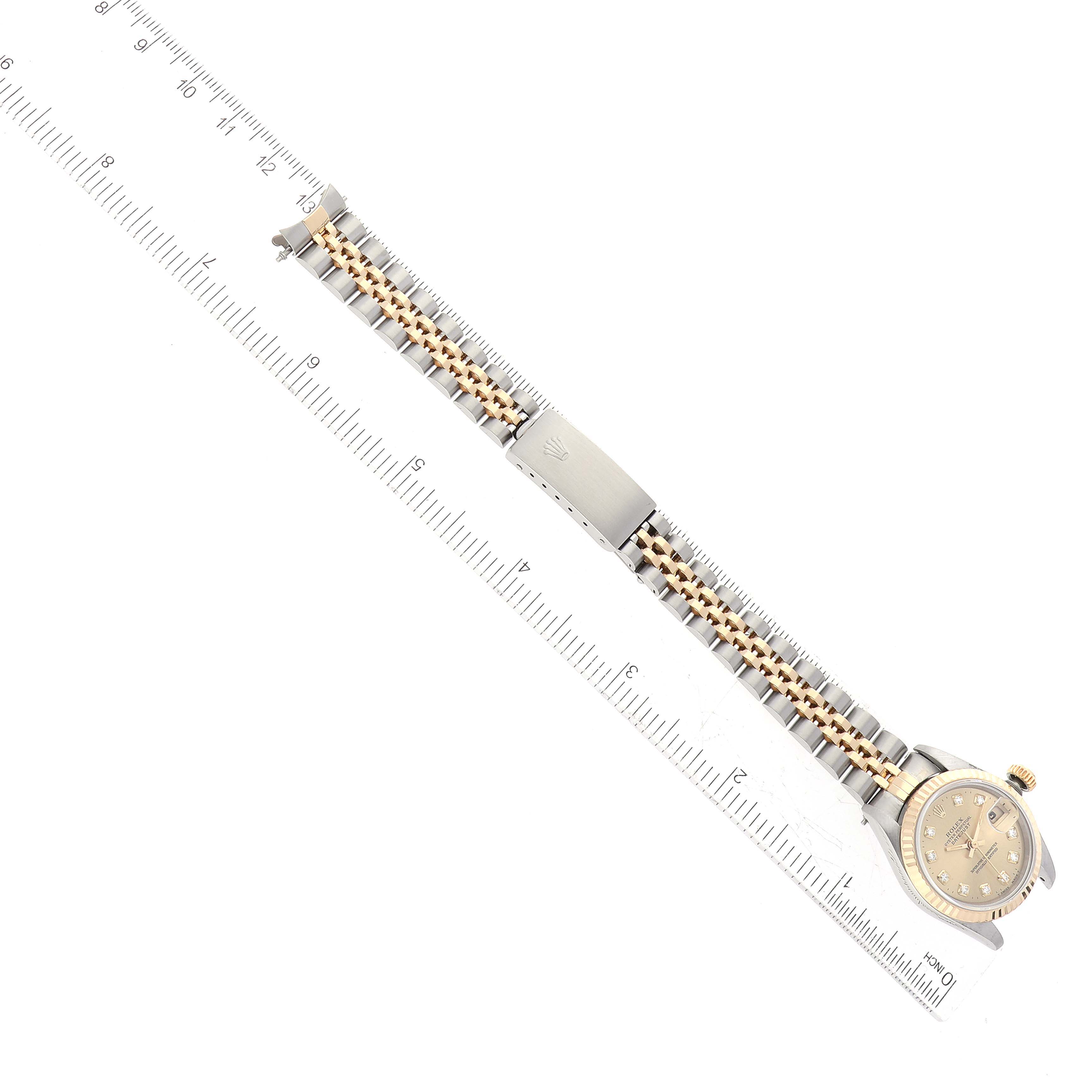 The image shows a top-down view of a Rolex Datejust 69173G Women's Steel and Gold (two tone) Champagne Dial 69173G Women's Steel and Gold (two tone) Champagne Dial watch featuring its face, bezel, and bracelet, which is laid flat next to a ruler.
