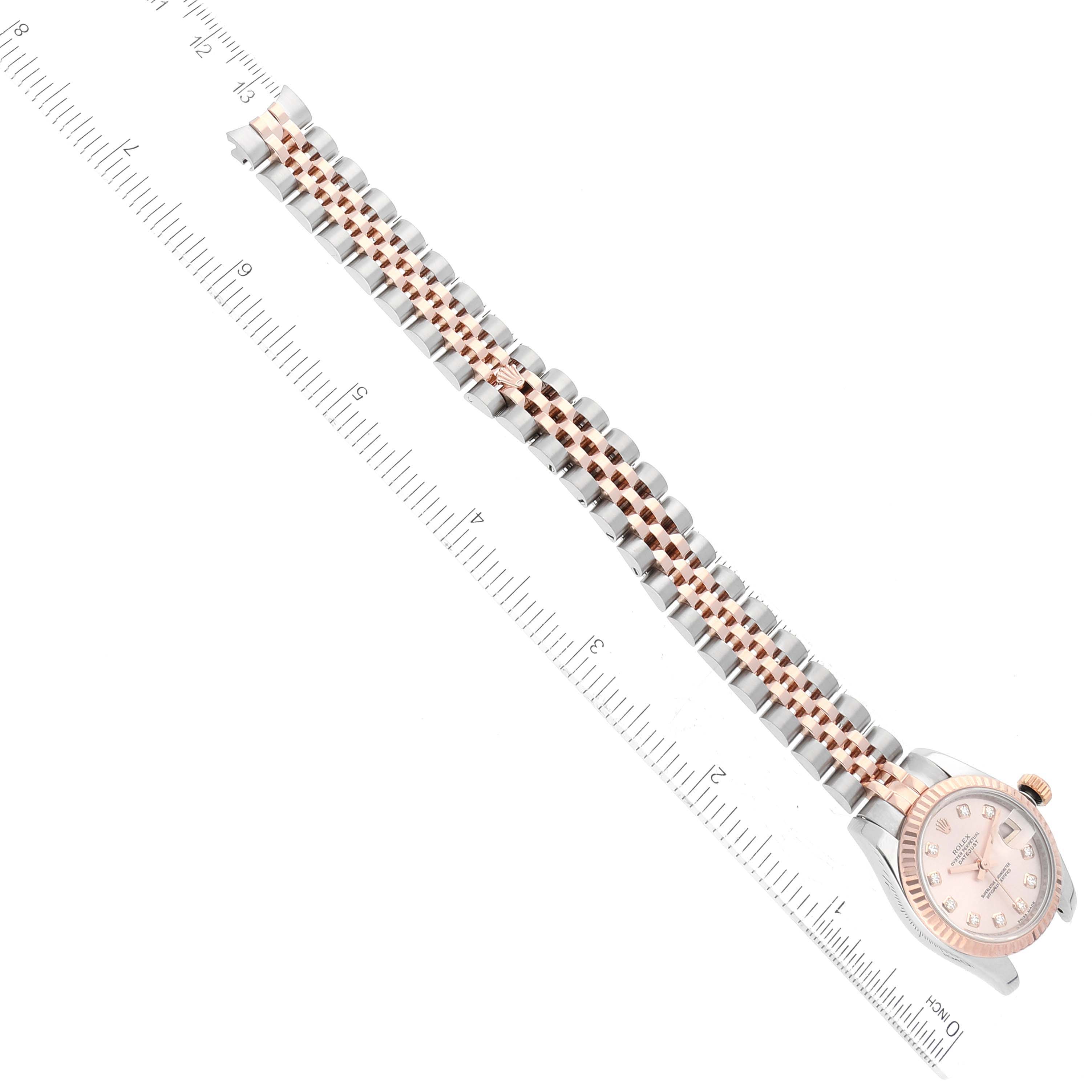 The image shows a top-down view of a Rolex Datejust 179171 Women's Steel and Gold (two tone) Pink Dial 179171 Women's Steel and Gold (two tone) Pink Dial watch, highlighting the watch face and bracelet against a ruler for scale.