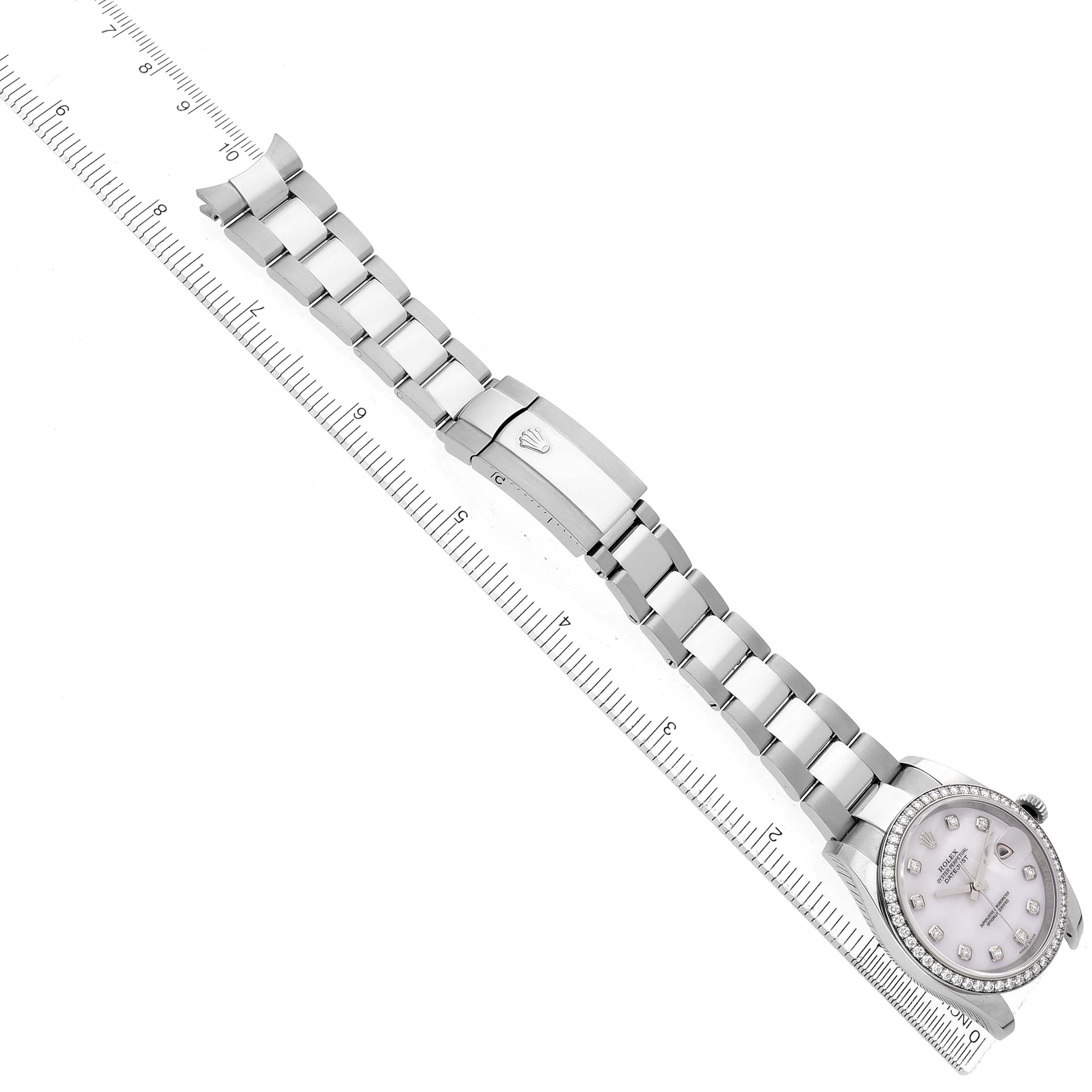 The Rolex Oyster Perpetual 116244 Men's Stainless Steel Mother of Pearl Dial is shown from an overhead angle, highlighting the band, clasp, and face alongside a ruler for scale.