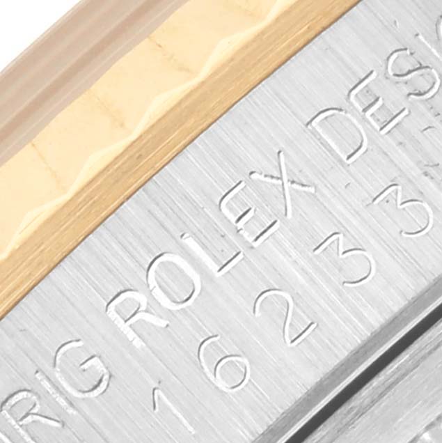 The image shows a close-up of the Rolex Datejust 16233 Men's Steel and Gold (two tone) White Dial 16233 Men's Steel and Gold (two tone) White Dial model's fluted bezel and engraved serial details.