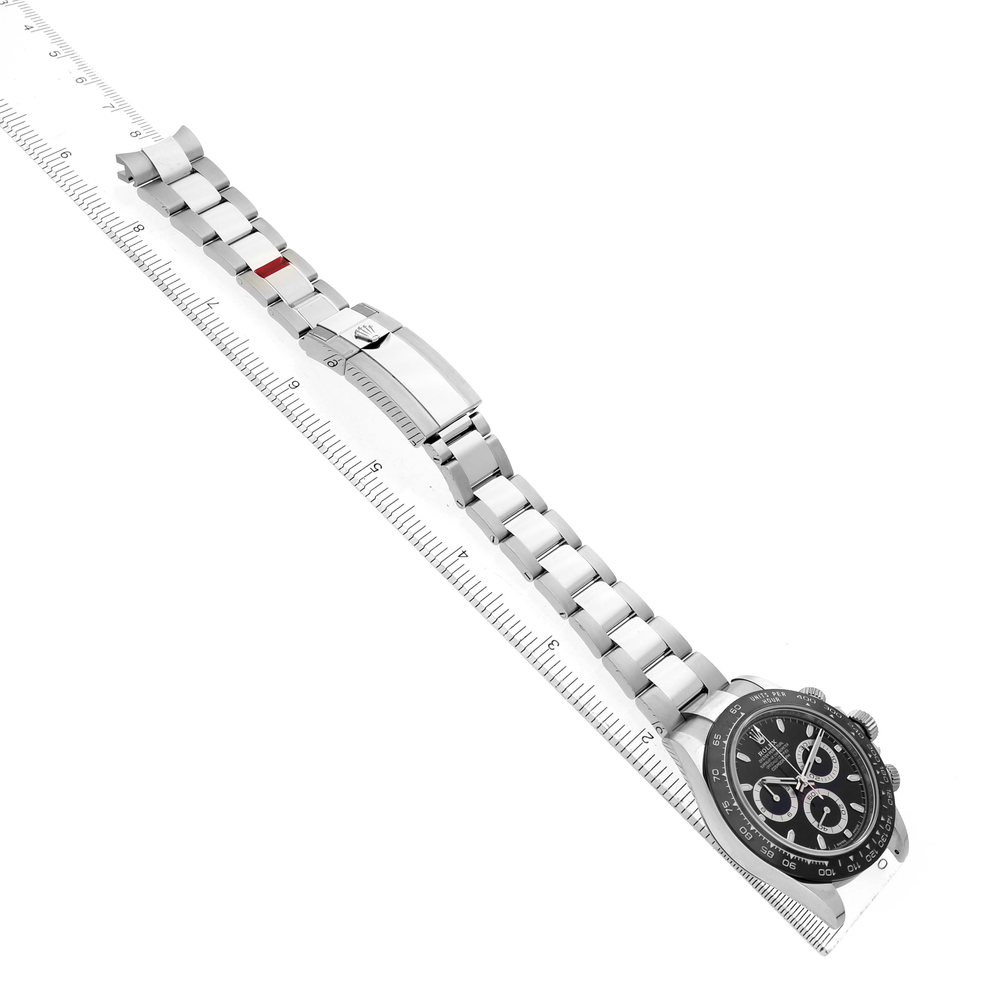The image shows a Rolex Daytona 116500LN Men's Stainless Steel Black Dial watch with a focus on the bracelet and clasp, viewed from a top angle alongside a ruler.