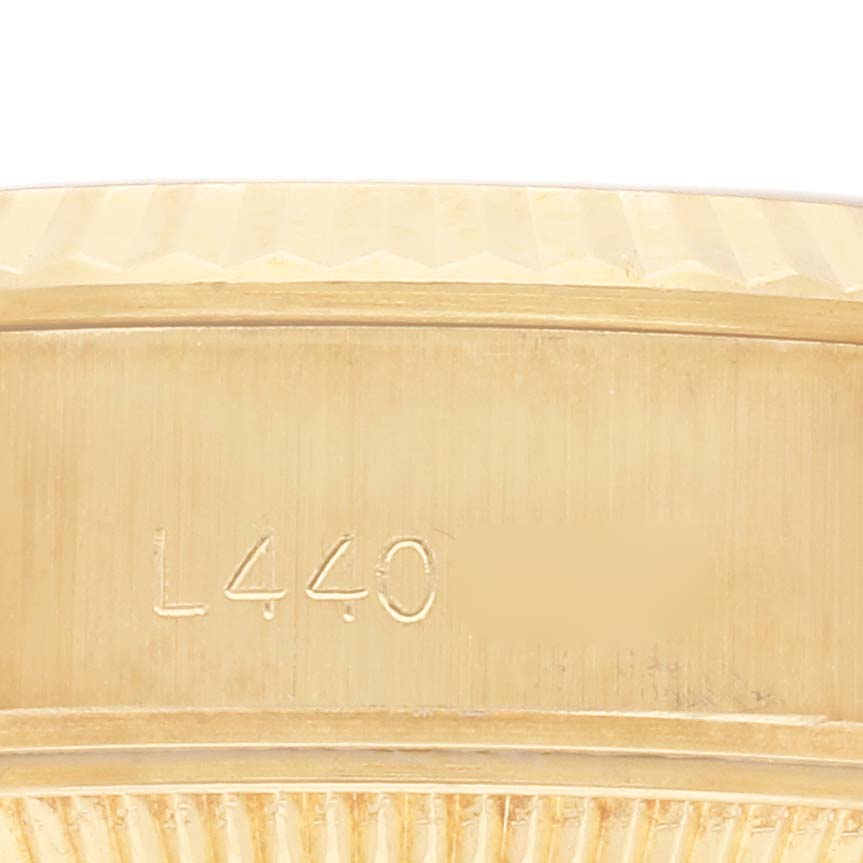 The image shows a close-up of the side of a Rolex President 69178 Women's Yellow Gold Champagne Dial 69178 Women's Yellow Gold Champagne Dial model, focusing on the gold case with engraved markings.