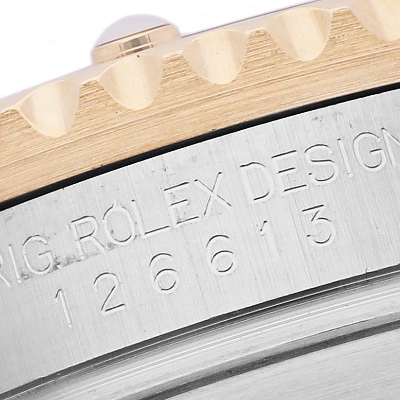 The image shows a close-up of the Rolex Submariner 126613LN Men's Steel and Gold (two tone) Black Dial 126613LN Men's Steel and Gold (two tone) Black Dial's bezel and engraved serial number on the side case.