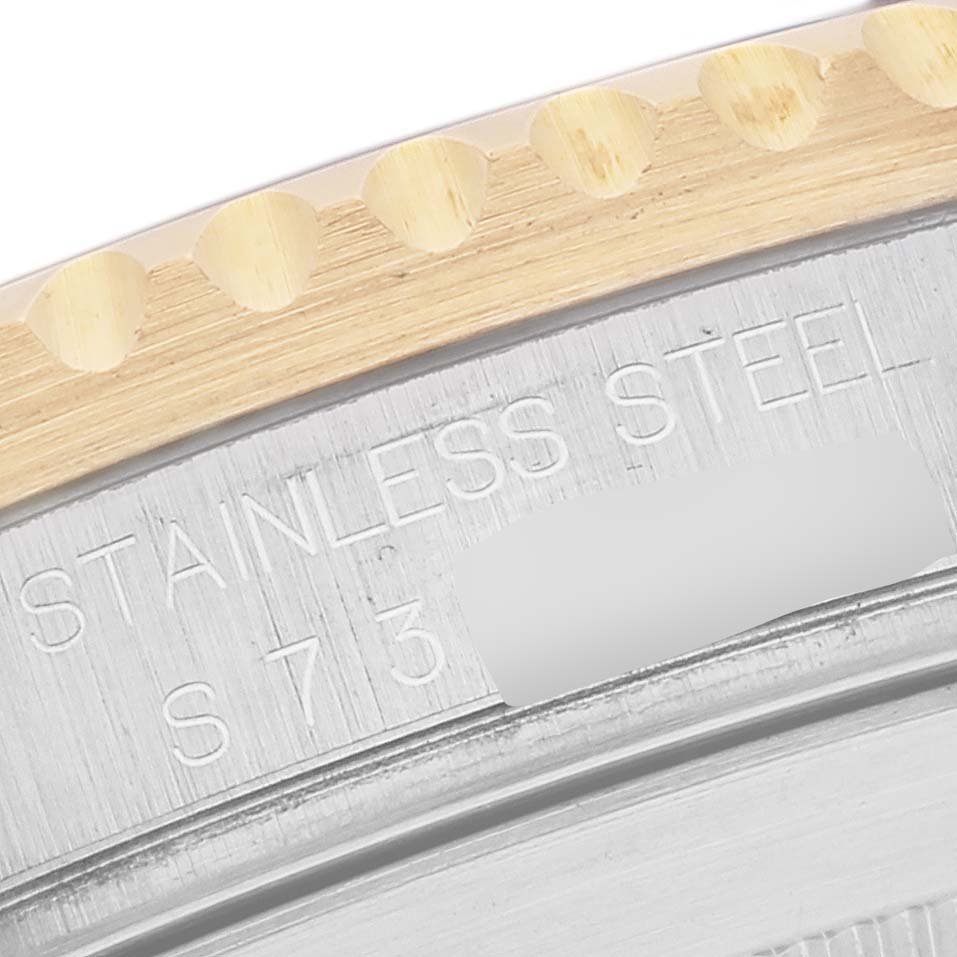 The image shows a close-up of the edge of a Rolex Submariner 16613 Men
s Steel and Gold (two tone) Blue Dial 16613 Men
s Steel and Gold (two tone) Blue Dial
s bezel and the engraved text on its stainless steel case back.