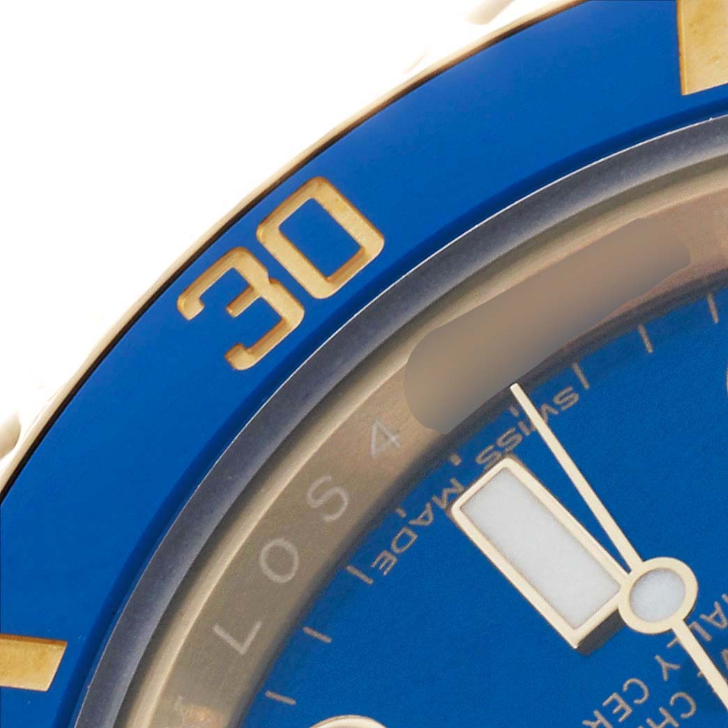 The image shows a close-up of the Rolex Submariner 116618LB Men's Yellow Gold Blue Dial's blue bezel and part of the dial with minute markers.