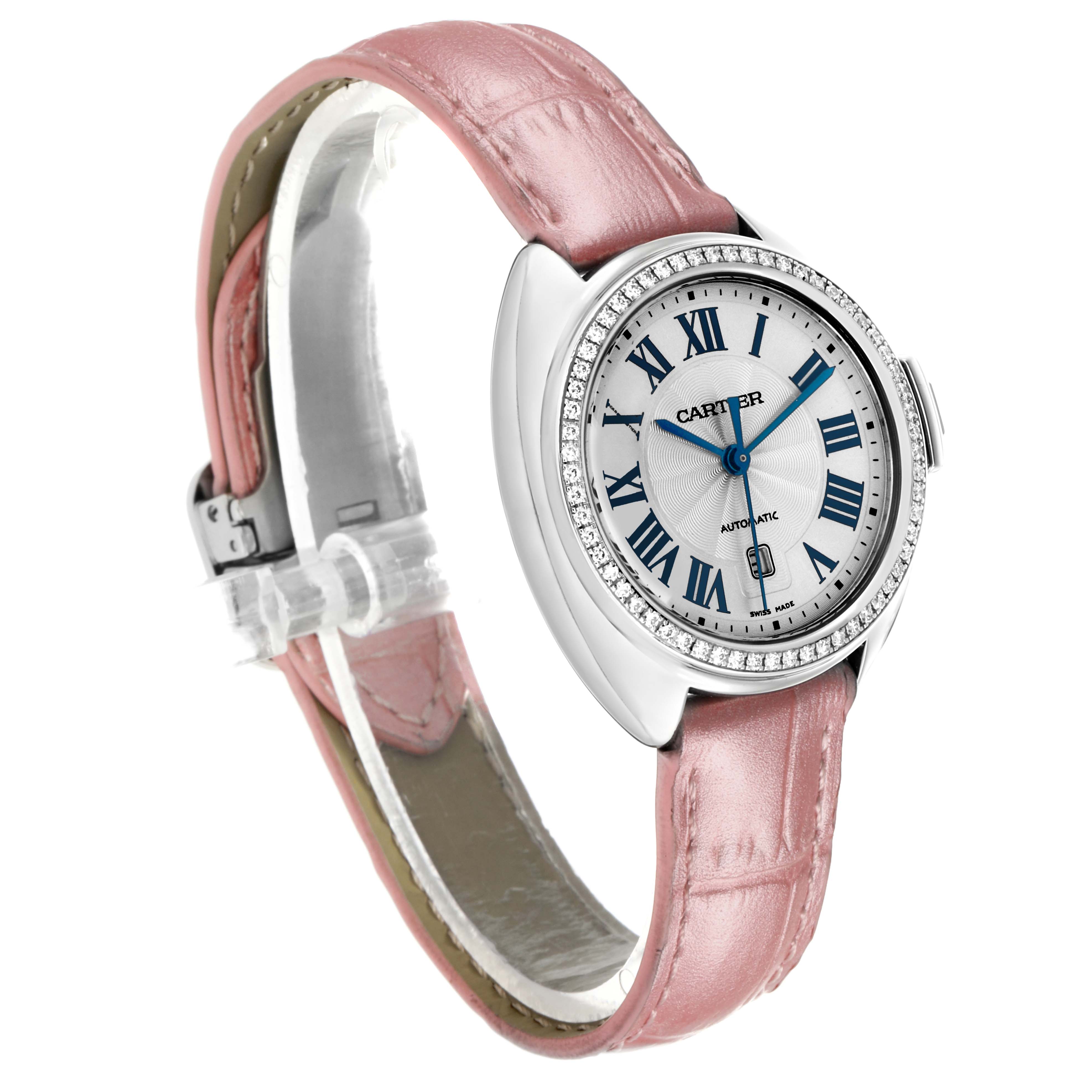 The Cle de Cartier watch is shown from a three-quarter angle, highlighting its pink strap, round bezel with diamonds, and Roman numeral dial.