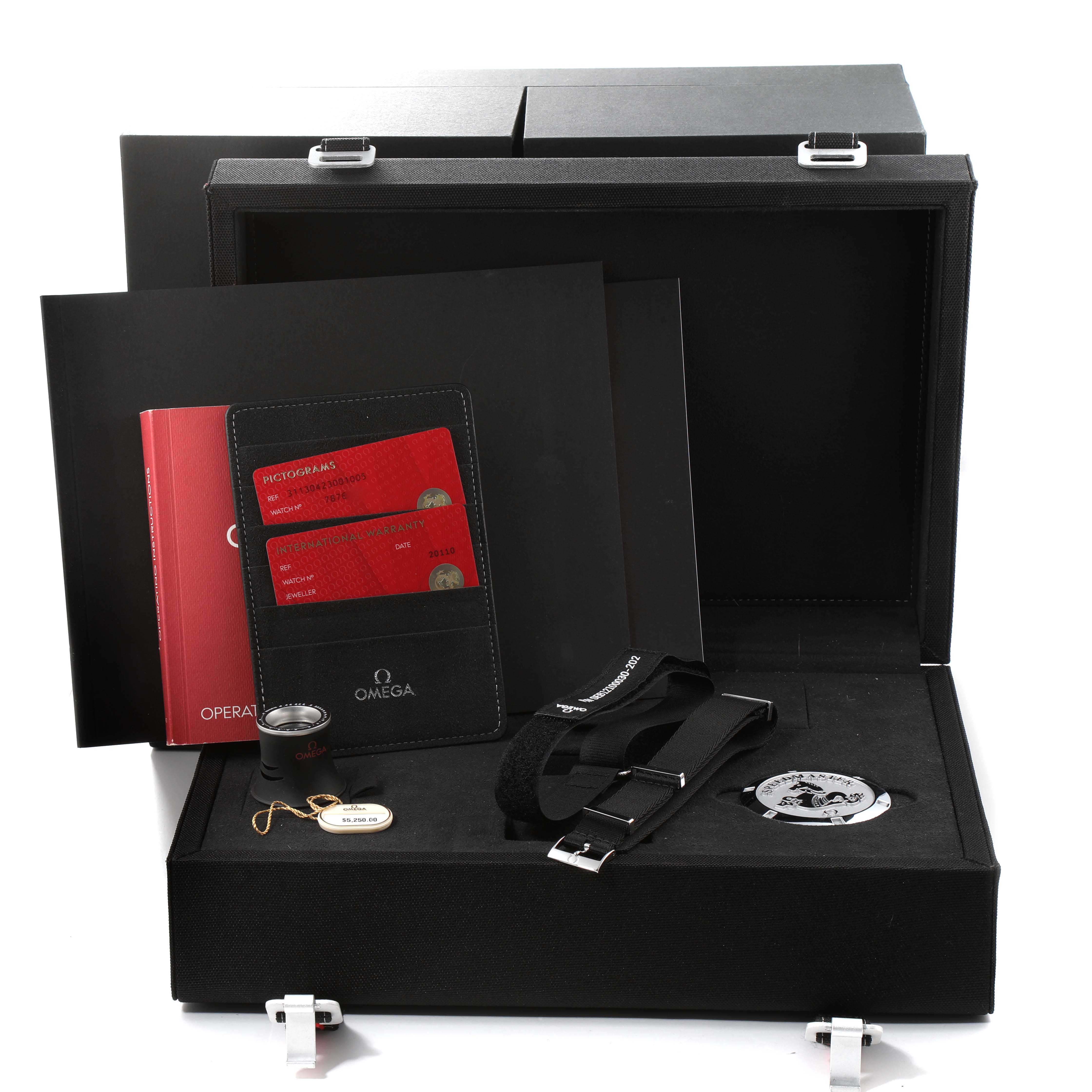 The image shows a box with accessories for the Speedmaster model by Omega, including booklets, straps, and warranty cards.