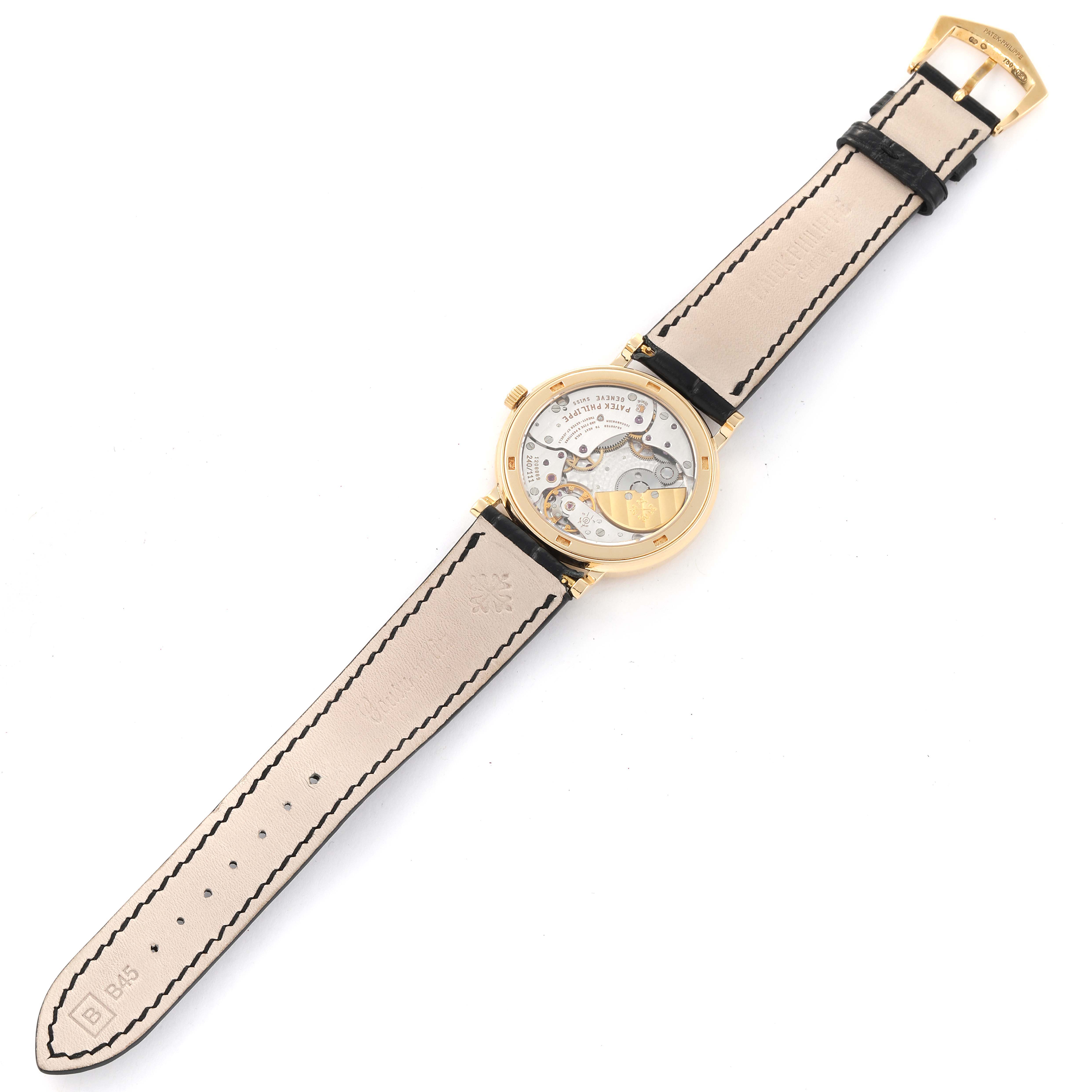 The image shows the backside of a Patek Philippe Calatrava 5120J Men's Yellow Gold White Dial 5120J Men's Yellow Gold White Dial watch, highlighting its leather strap and internal mechanical movements.