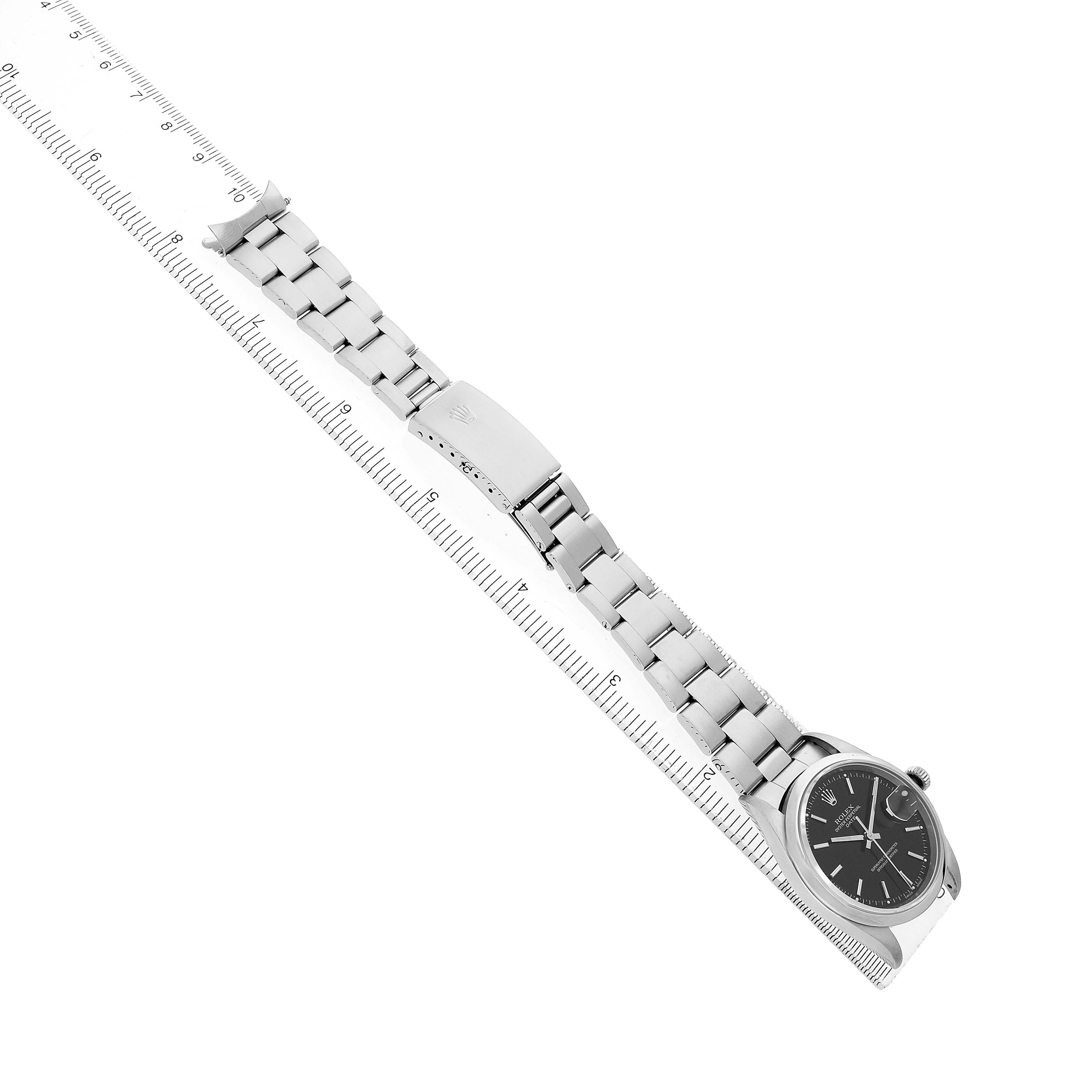 The Rolex Date 15200 Men's Stainless Steel Black Dial watch is shown at an angled top view, highlighting its bracelet and face, alongside a ruler for size reference.