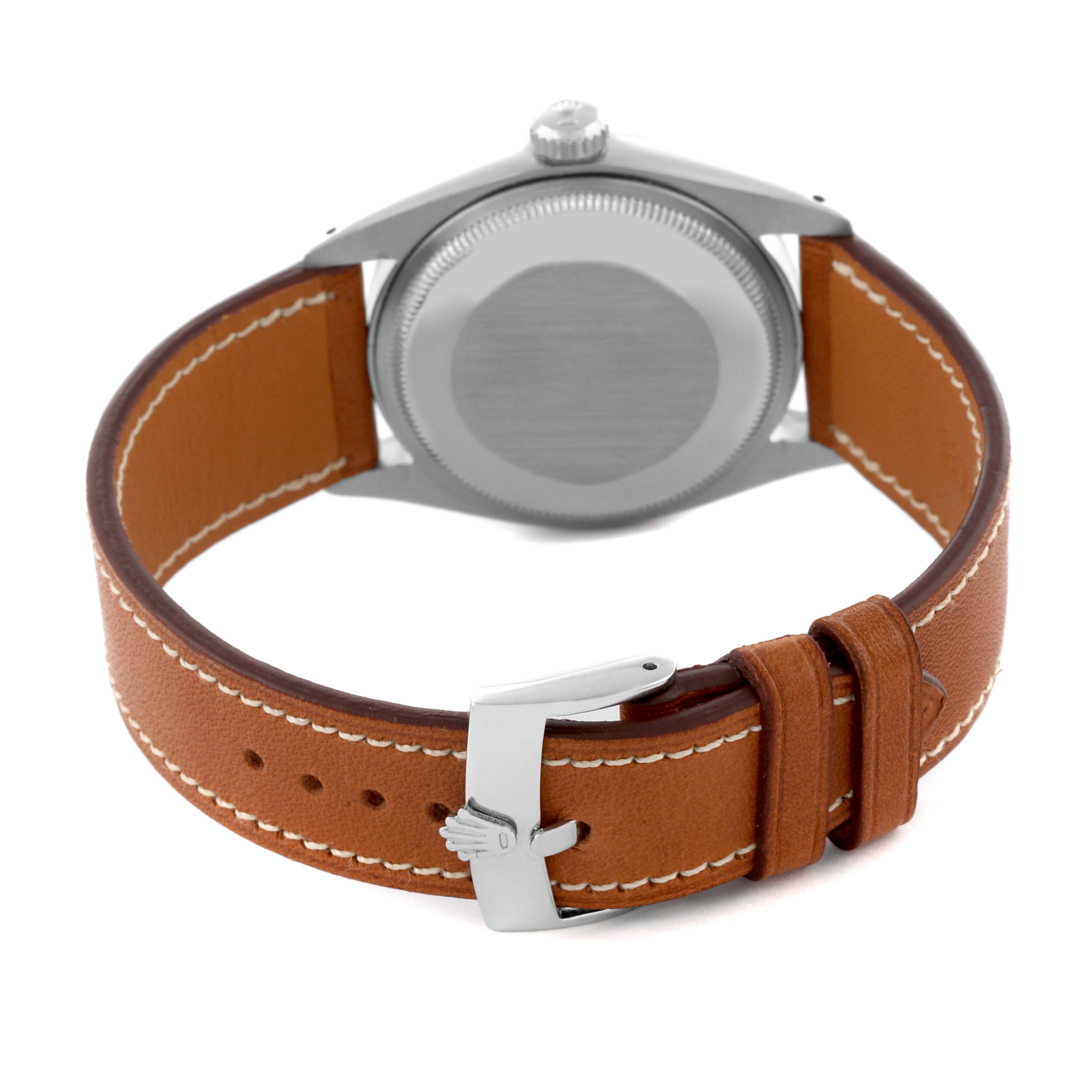 The image shows the back of a Rolex Date 1500 Men's Stainless Steel Silver Dial 1500 Men's Stainless Steel Silver Dial watch case and a tan leather strap with a metal buckle.