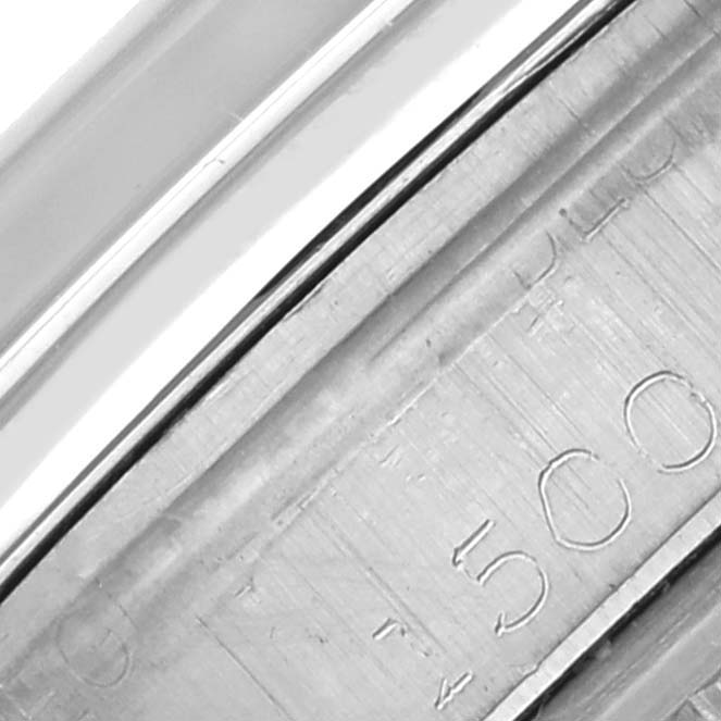 The image shows a close-up of the edge of a Rolex Date 1500 Men's Stainless Steel Silver Dial 1500 Men's Stainless Steel Silver Dial model watch with engraved details visible.