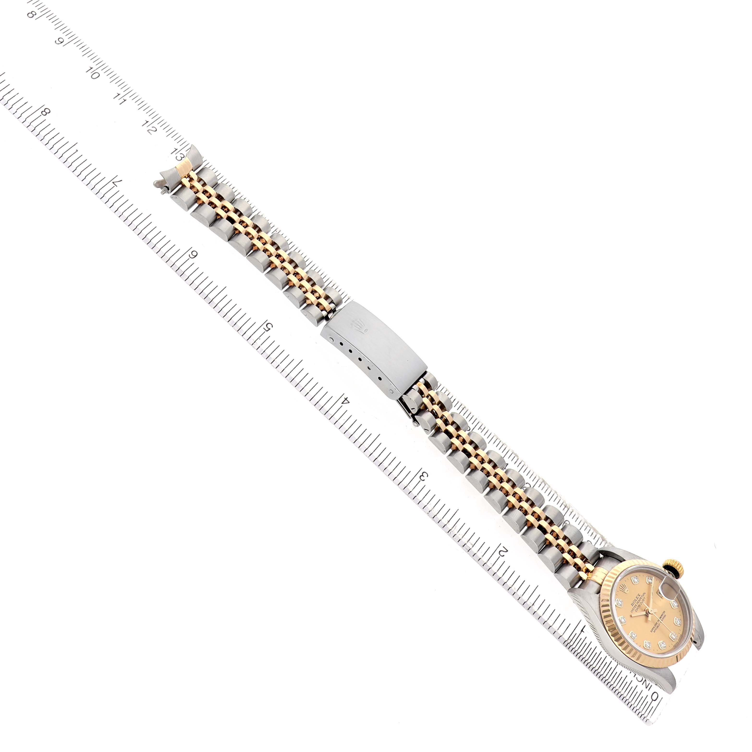 The image shows a Rolex Datejust 69173 Women's Steel and Gold (two tone) Champagne Dial watch from an overhead angle, featuring the bracelet, clasp, and face aligned with a ruler.