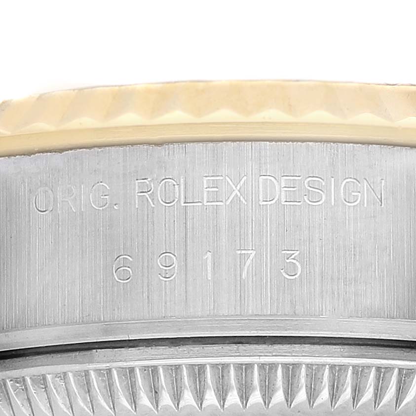 The image shows a close-up of the side view of the case back of a Rolex Datejust 69173 Women's Steel and Gold (two tone) Champagne Dial, highlighting its engraved design and model number.