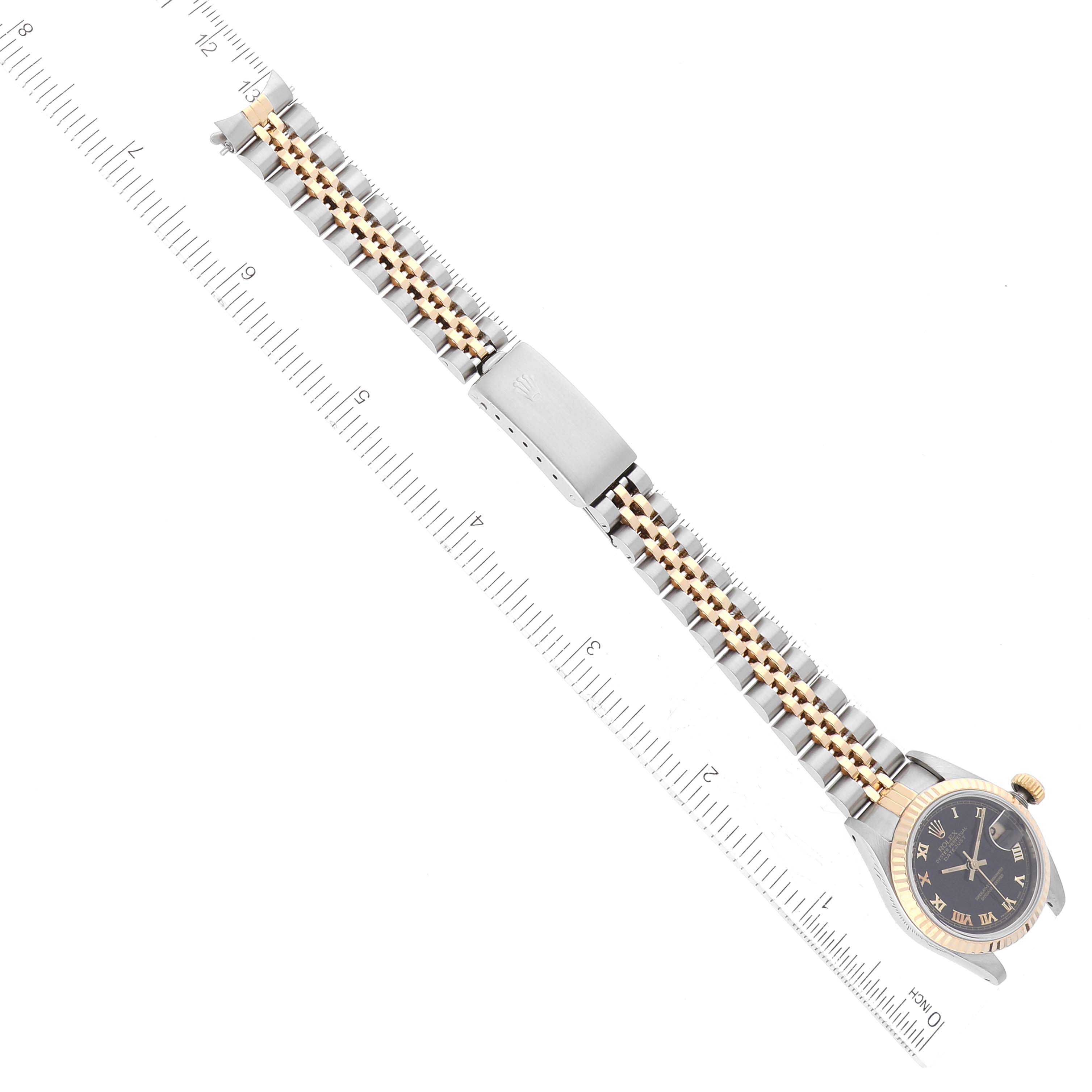 The Rolex Datejust 69173 Women's Steel and Gold (two tone) Black Dial 69173 Women's Steel and Gold (two tone) Black Dial watch is shown from a top-down angle, displaying its face, bezel, and bracelet with a ruler for scale.