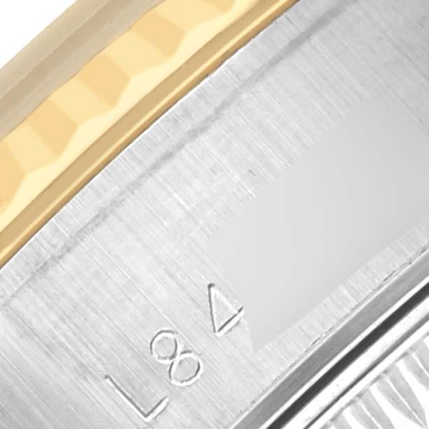 The image shows a close-up of a Rolex Datejust 69173 Women's Steel and Gold (two tone) Black Dial 69173 Women's Steel and Gold (two tone) Black Dial's metal surface with visible engravings and part of the gold and silver bracelet.