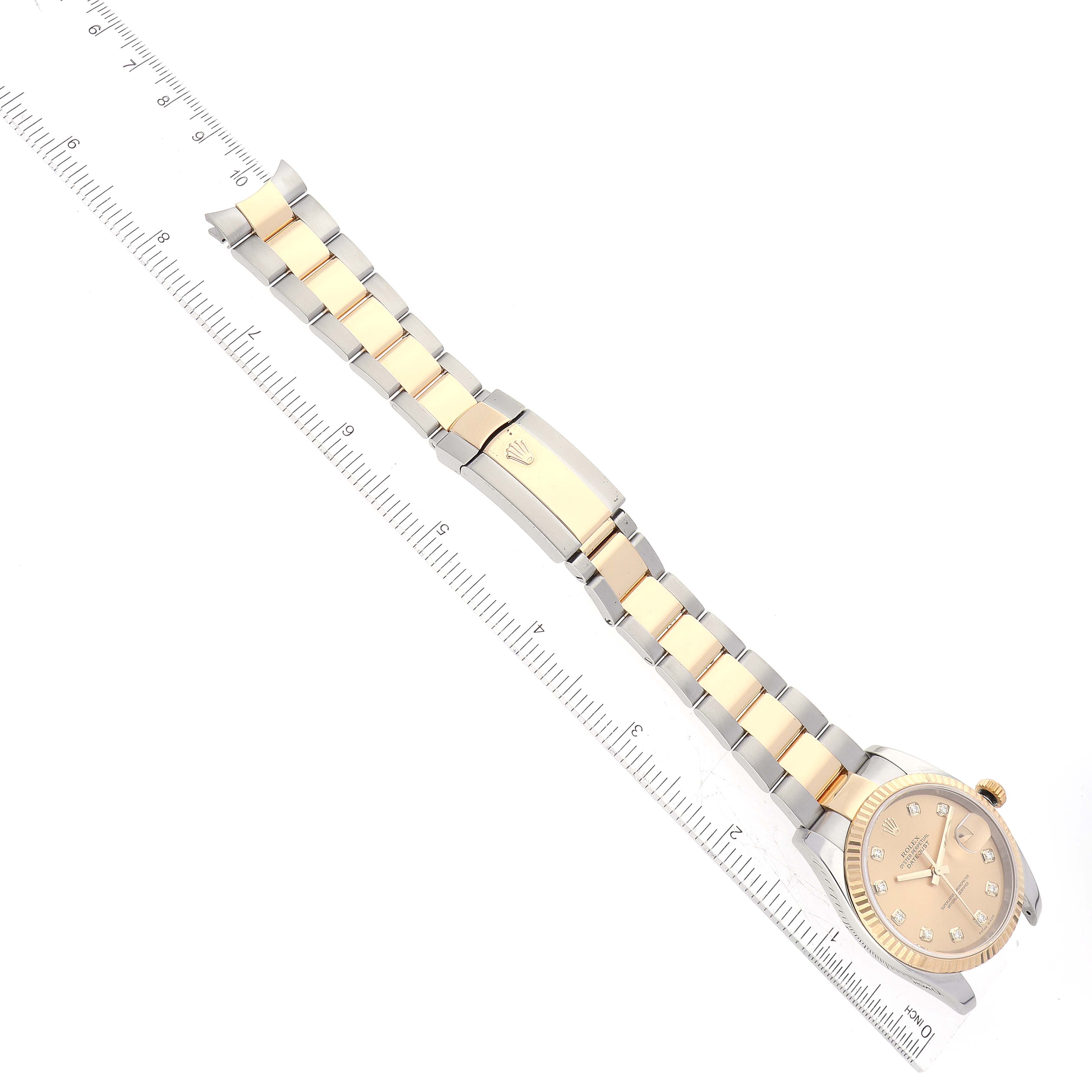 The image shows a top-down view of a Rolex Datejust 116233 Men's Steel and Gold (two tone) Champagne Dial 116233 Men's Steel and Gold (two tone) Champagne Dial watch, including its face and two-tone bracelet with a ruler alongside for scale.