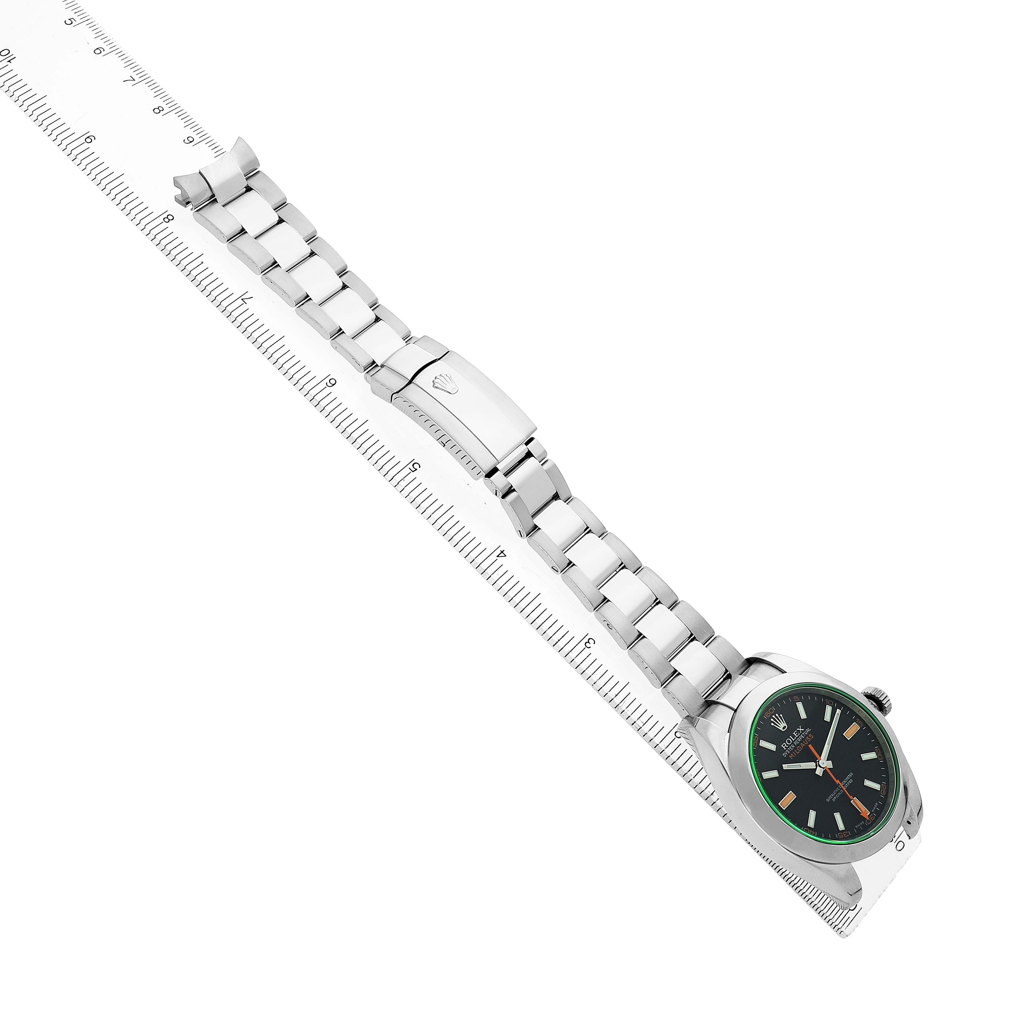 The Rolex Milgauss 116400GV Men's Stainless Steel Black Dial watch is shown at an angle with its stainless steel strap and clasp fully extended alongside a ruler.