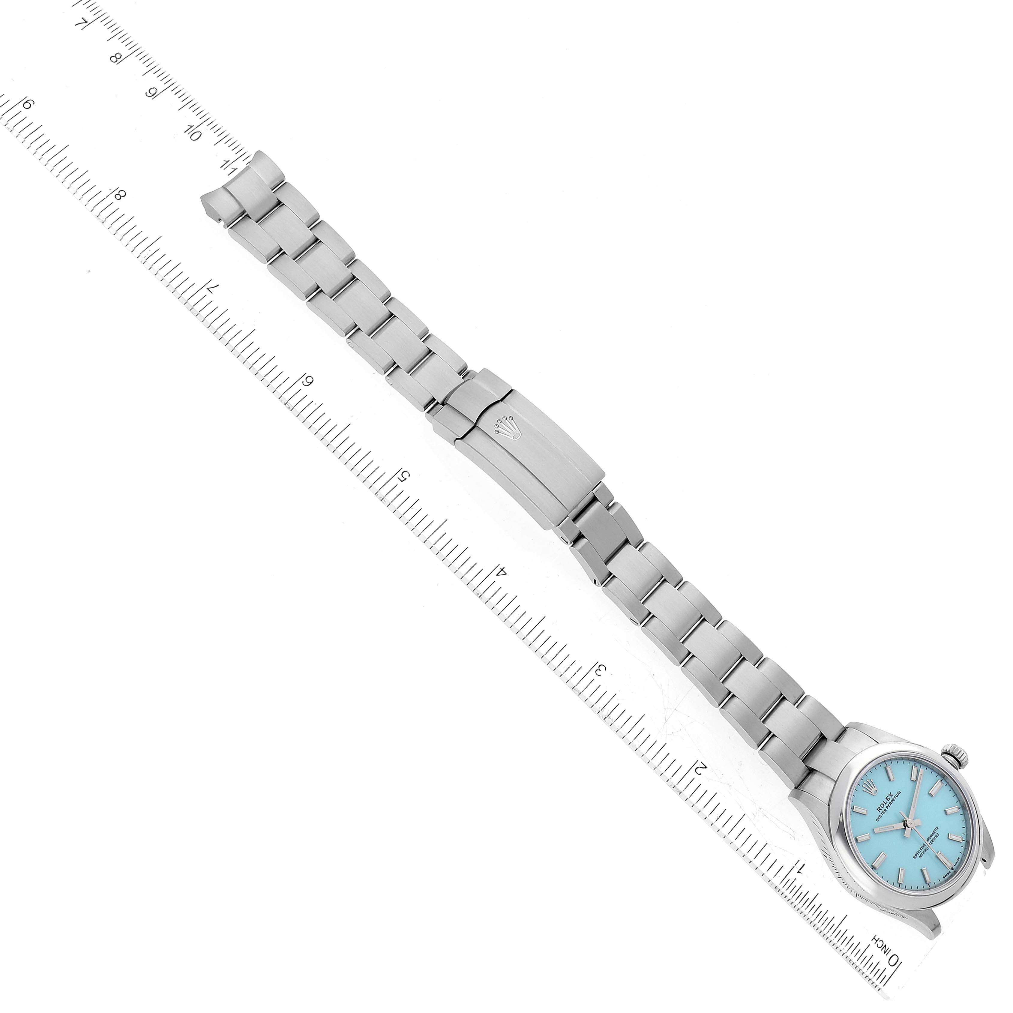 This image shows a Rolex Mid-Size 277200 Women's Stainless Steel Blue Dial 277200 Women's Stainless Steel Blue Dial watch lying flat with a ruler for scale, displaying the watch's face, bracelet, and clasp.