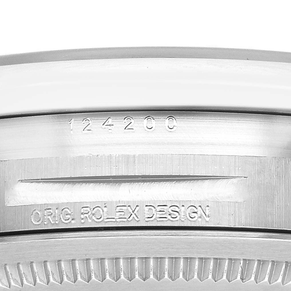 The image shows the side edge of the Rolex Oyster Perpetual 124200 Men's Stainless Steel Blue Dial watch, highlighting its model number and "Orig. Rolex Design" engraving.