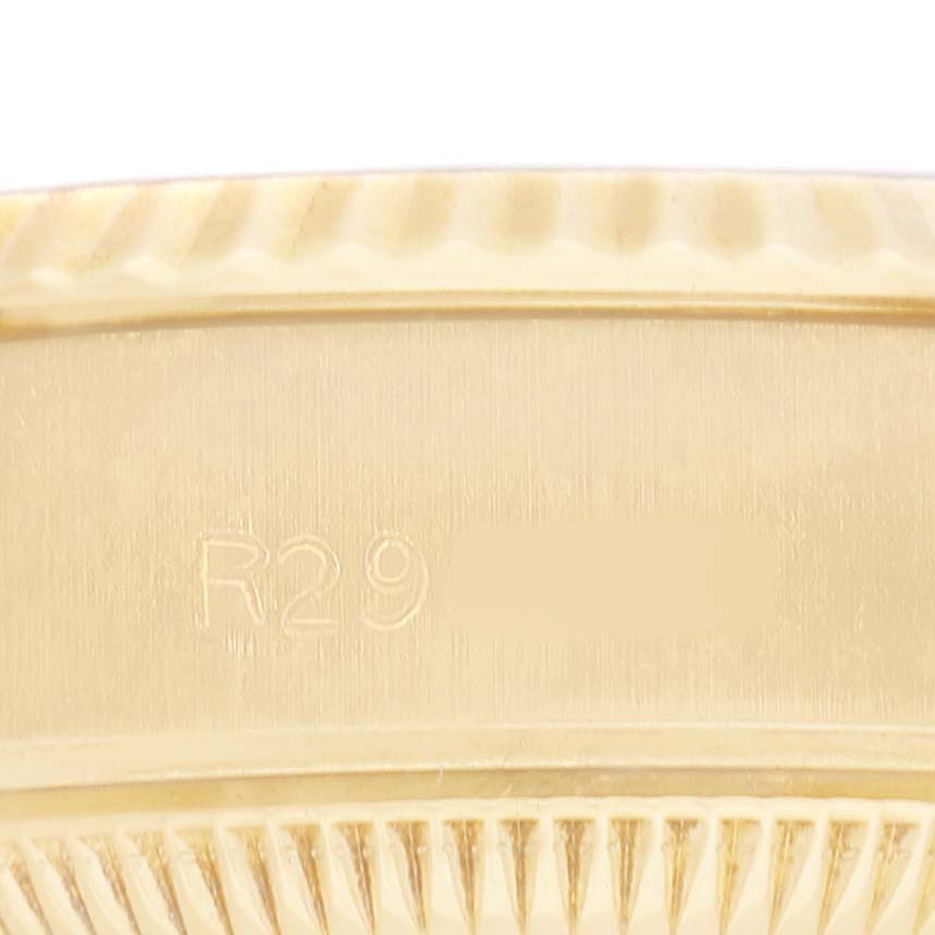 The image shows a close-up of the edge of a Rolex President 69178 Women's Yellow Gold Champagne Dial model, focusing on the serial number and fluted bezel.