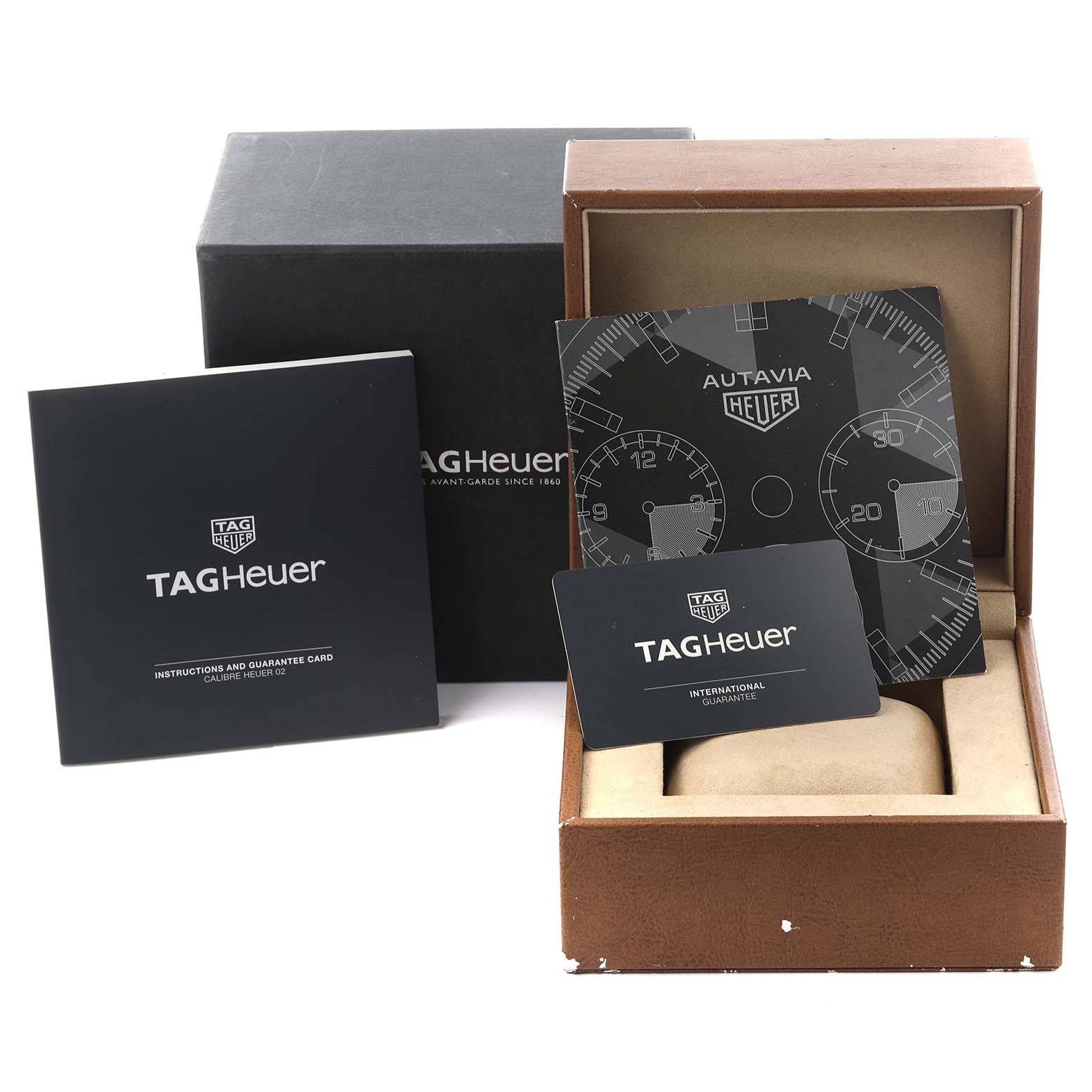 The image shows a Tag Heuer Autavia CBE2110.BA0687 Men's Stainless Steel Black Dial CBE2110.BA0687 Men's Stainless Steel Black Dial watch box, instruction manual, dial, and guarantee card from an angled view.