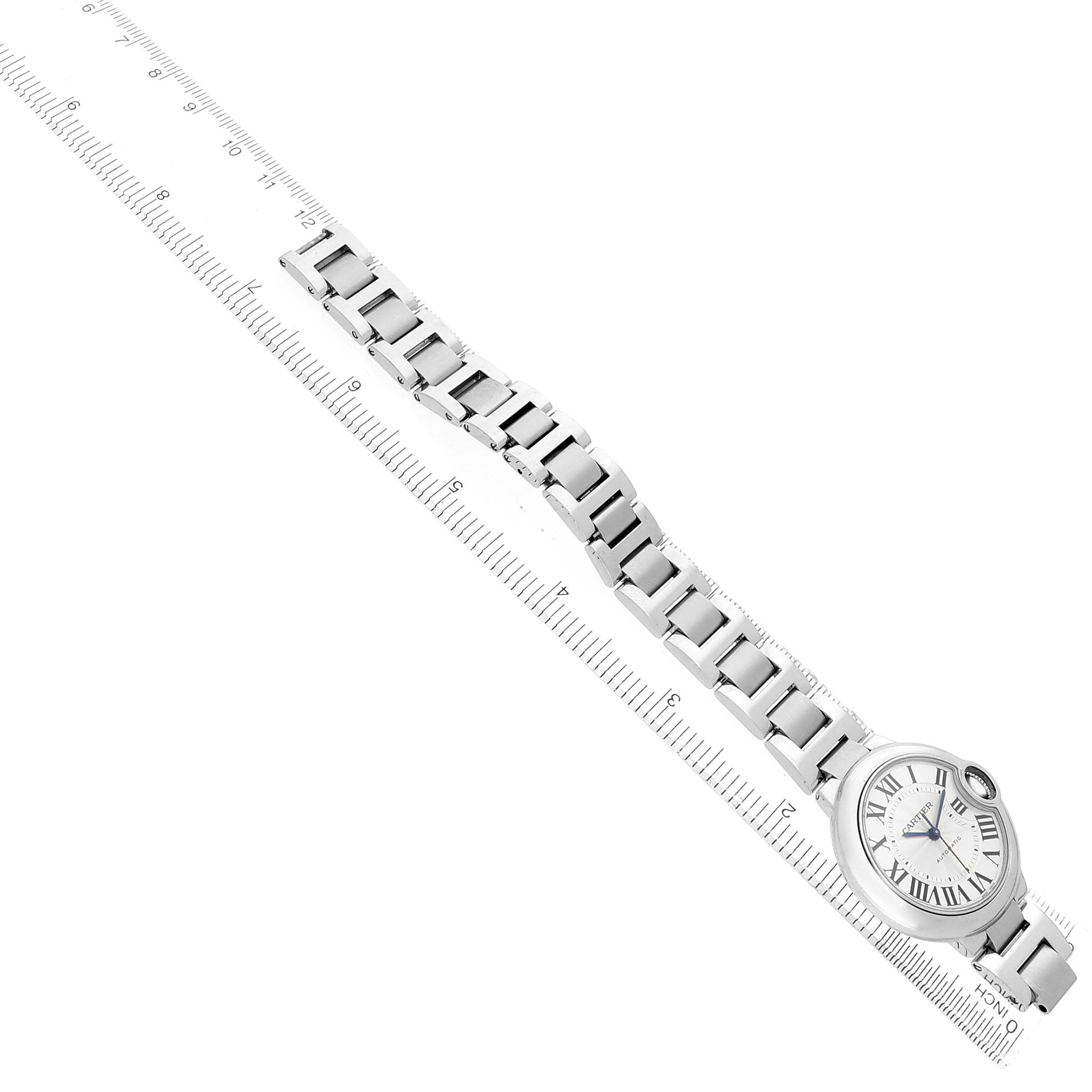 The Cartier Ballon Bleu W6920071 Women's Stainless Steel Silver Dial watch is shown at a diagonal angle, highlighting the bracelet and face on a ruler.