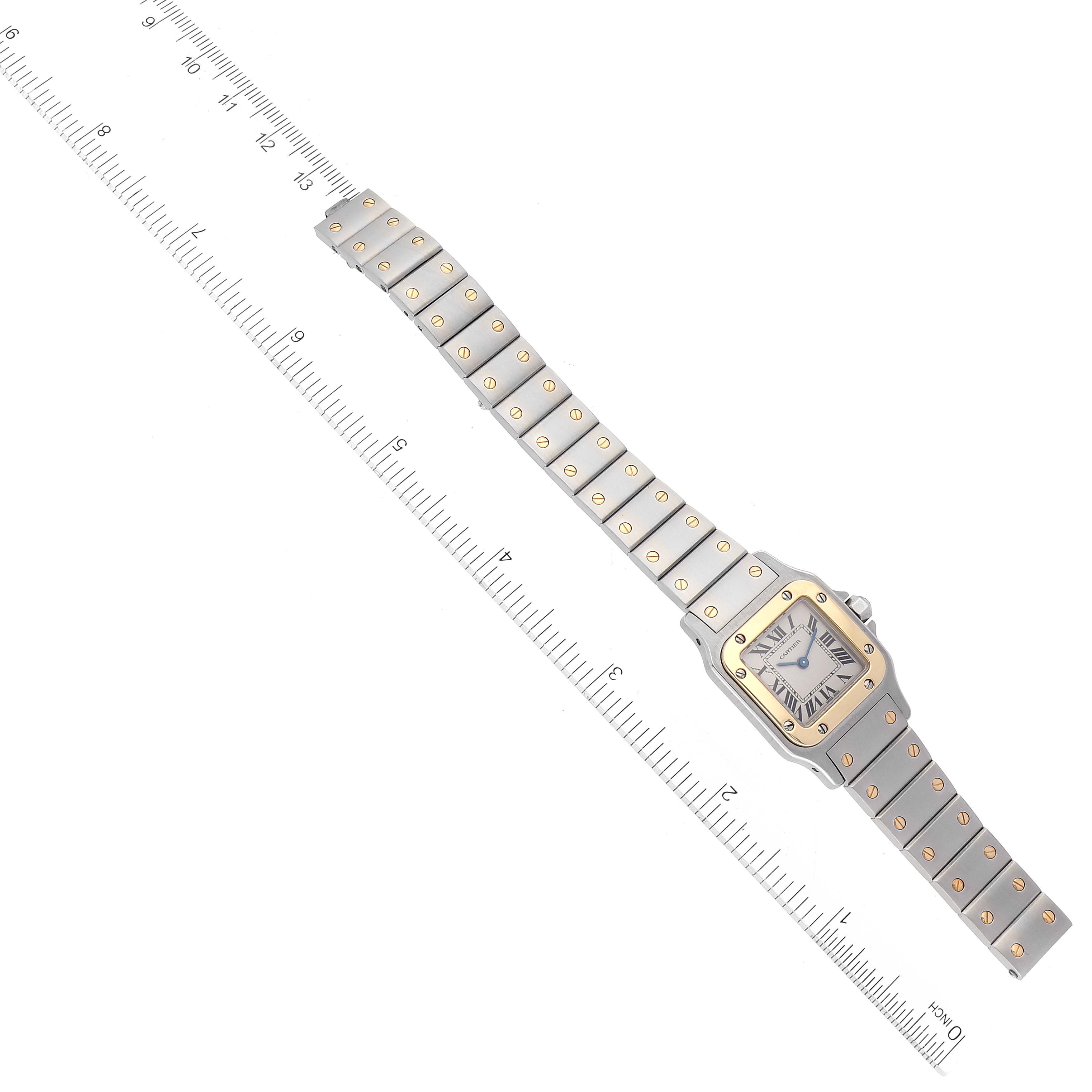 The Cartier Santos W20012C4 Women's Steel and Gold (two tone) Silver Dial W20012C4 Women's Steel and Gold (two tone) Silver Dial watch is shown from a top-down angle, featuring the entire watch and its band alongside a measuring ruler.