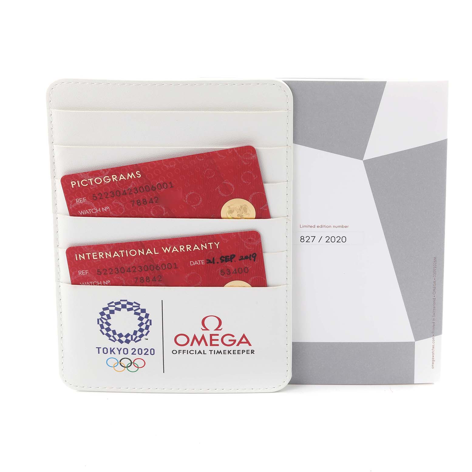 The image shows Omega Speedmaster 522.30.42.30.06.001 Men's Stainless Steel Silver Dial 522.30.42.30.06.001 Men's Stainless Steel Silver Dial accessories, including a warranty cardholder and box, viewed from the front.