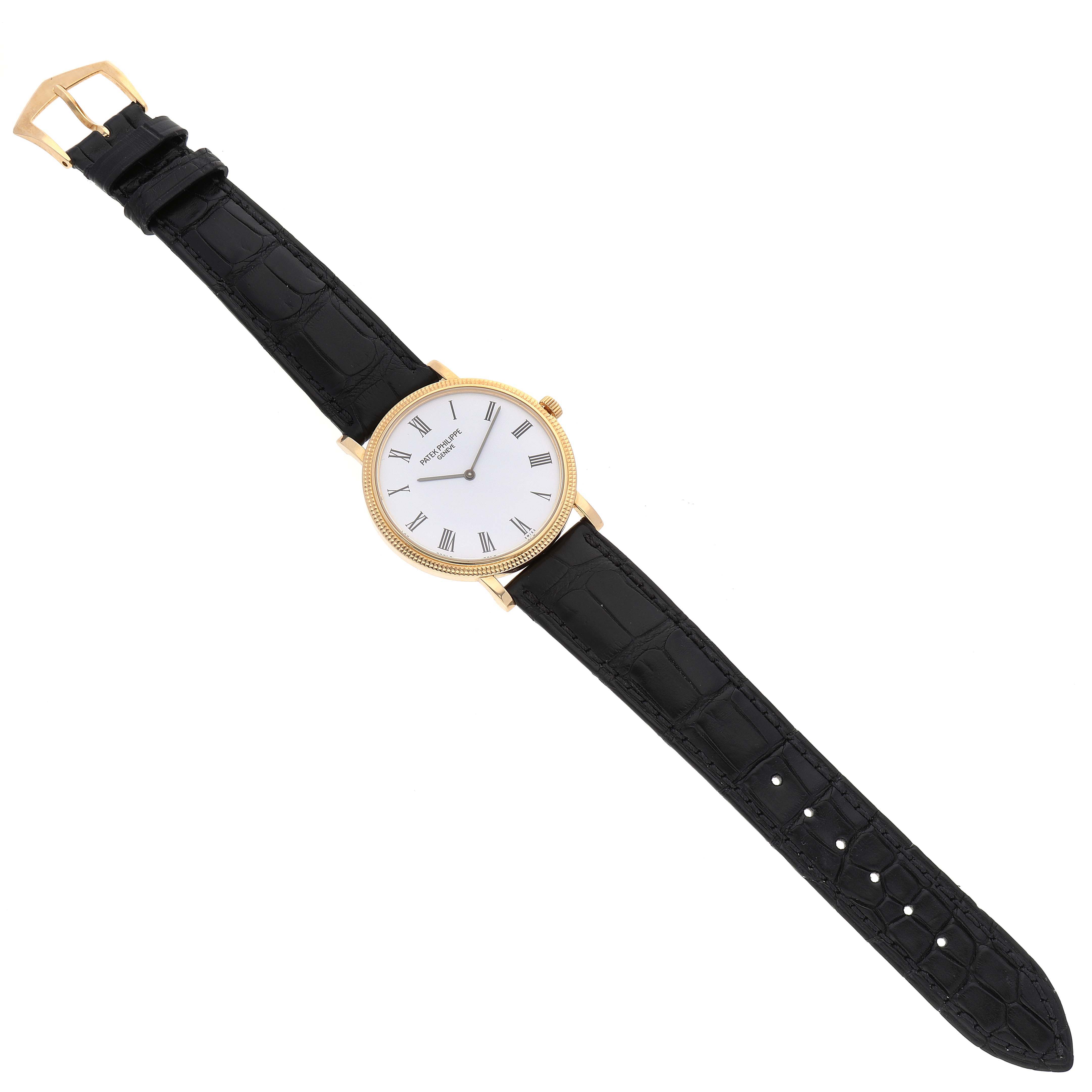 This image shows a Patek Philippe Calatrava 5120J Men's Yellow Gold White Dial 5120J Men's Yellow Gold White Dial watch from a top-down angle, highlighting the watch face, strap, and buckle.