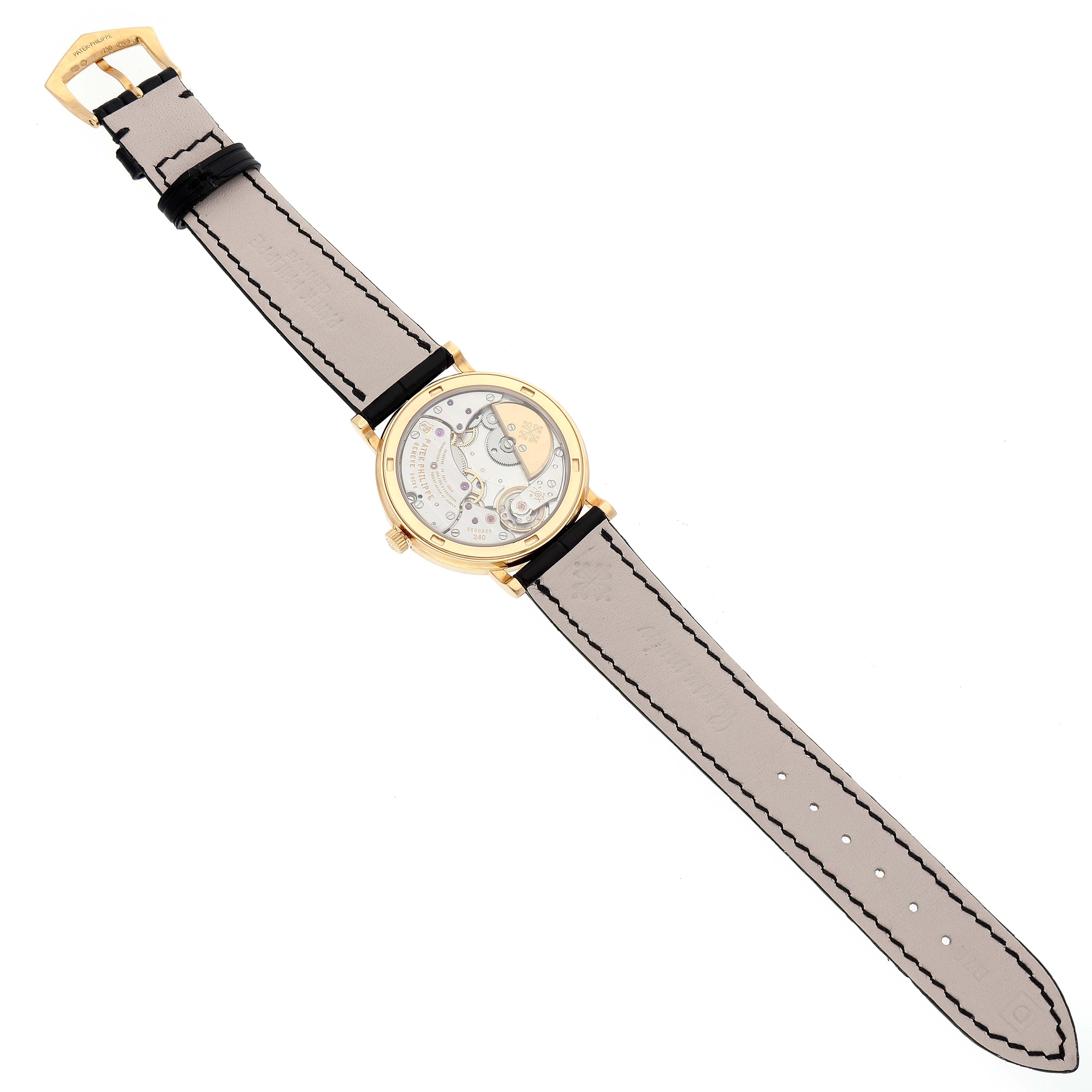 The image shows the backside of a Patek Philippe Calatrava 5120J Men's Yellow Gold White Dial 5120J Men's Yellow Gold White Dial watch, highlighting its movement mechanisms and leather strap.