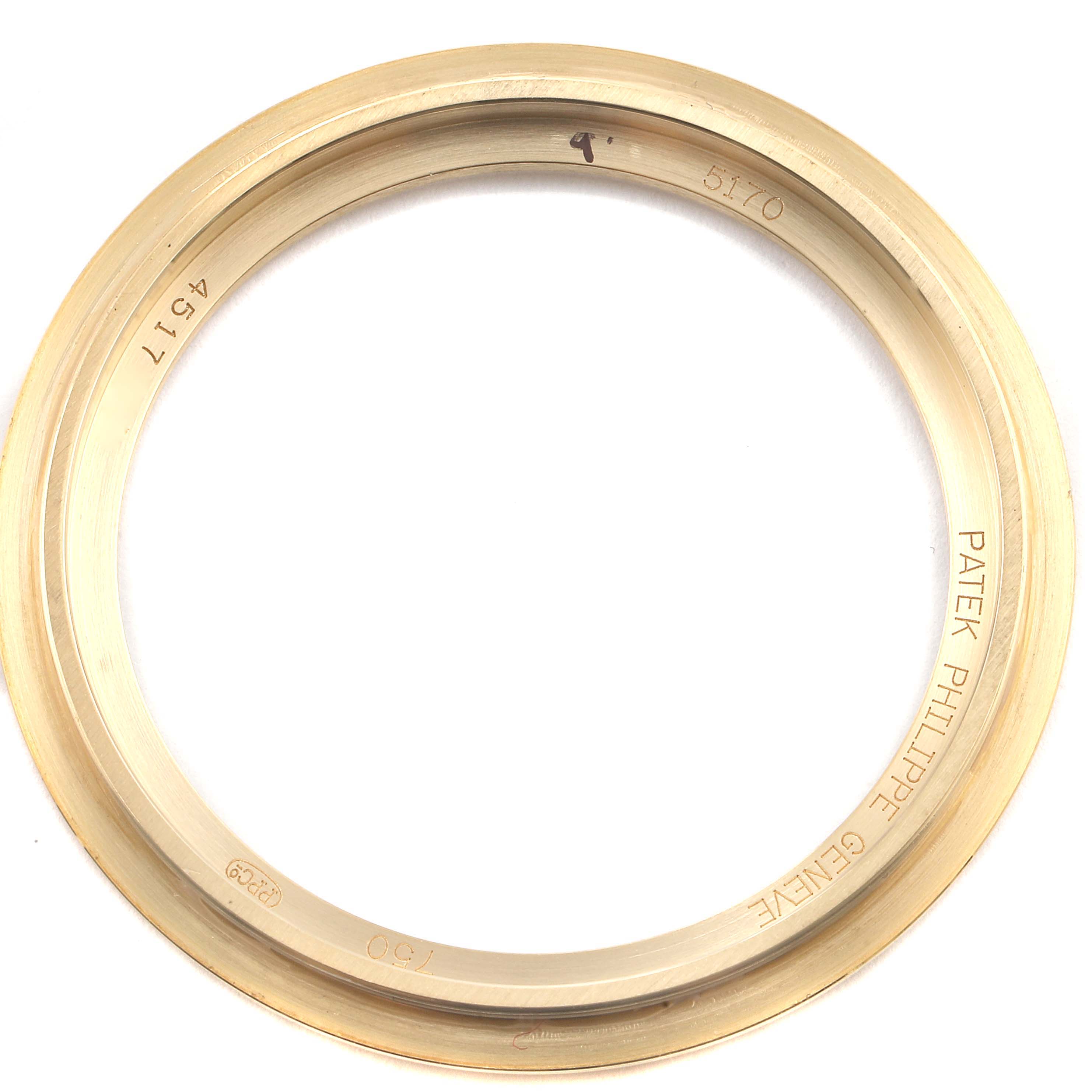 This is a top-view image of a bezel for a Patek Philippe Complications 5170J Men's Yellow Gold Silver Dial 5170J Men's Yellow Gold Silver Dial model watch, showcasing its gold ring and engraved details.