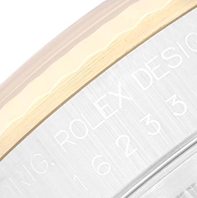 Close-up view of the engraved edge of a Rolex Datejust 16233 Men's Steel and Gold (two tone) Beige Dial 16233 Men's Steel and Gold (two tone) Beige Dial model, showing part of the bezel and case.